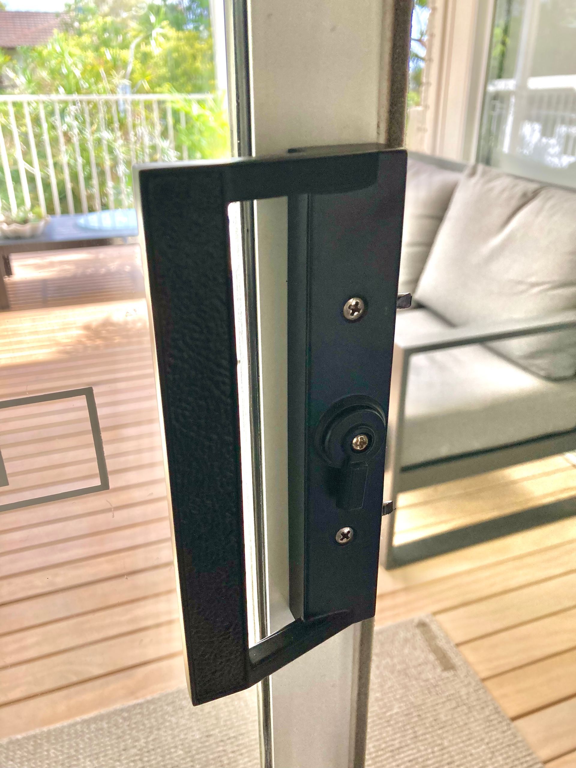 Black sliding glass door handle with lock; exterior view of deck and seating— Fix-A-Door in Morisset, NSW