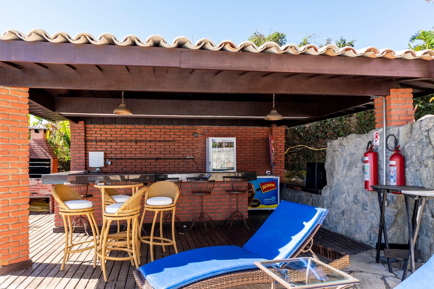 Um prédio de tijolos com um bar e cadeiras sob um telhado.