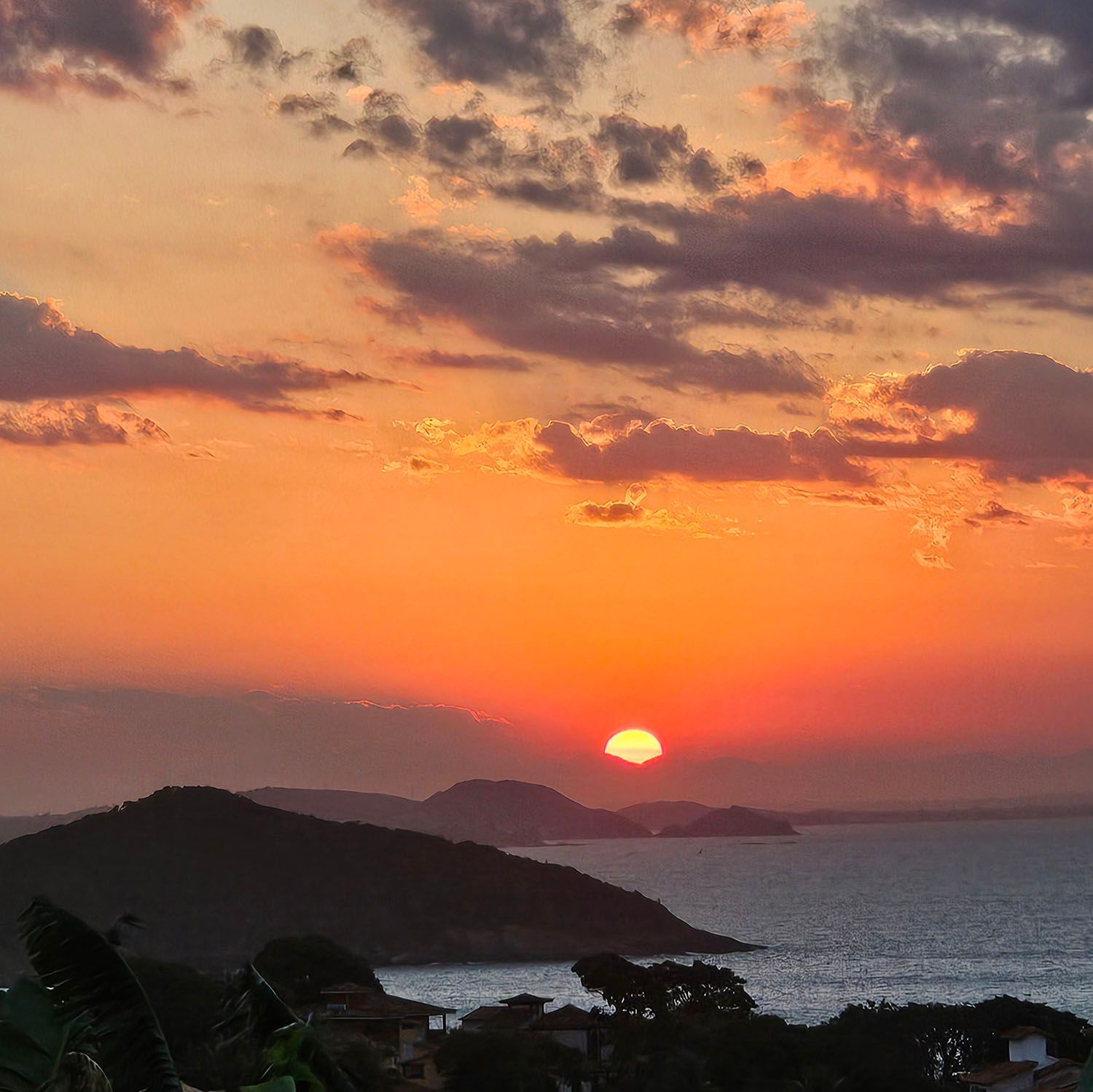 Um pôr do sol sobre um corpo de água com montanhas ao fundo