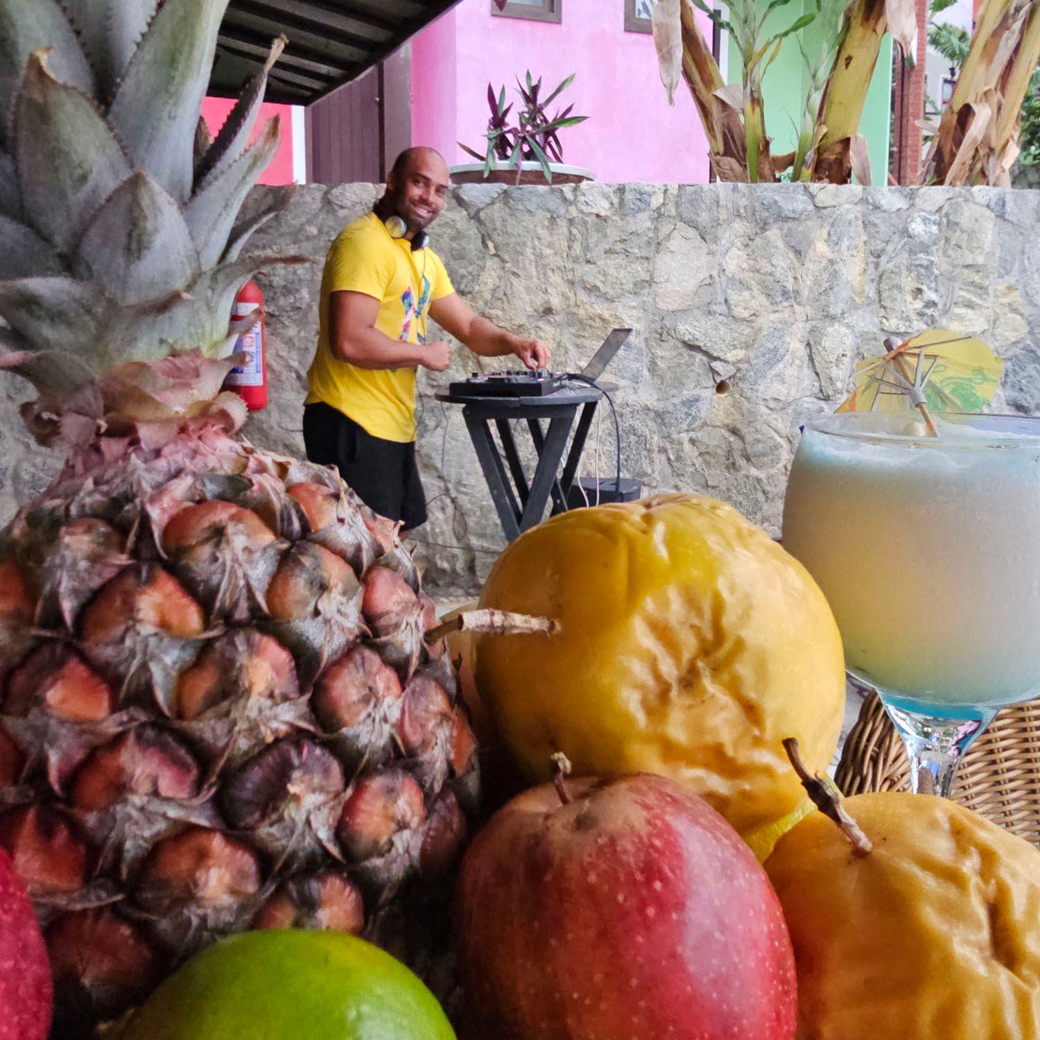 Um homem de camisa amarela está usando um laptop cercado por frutas