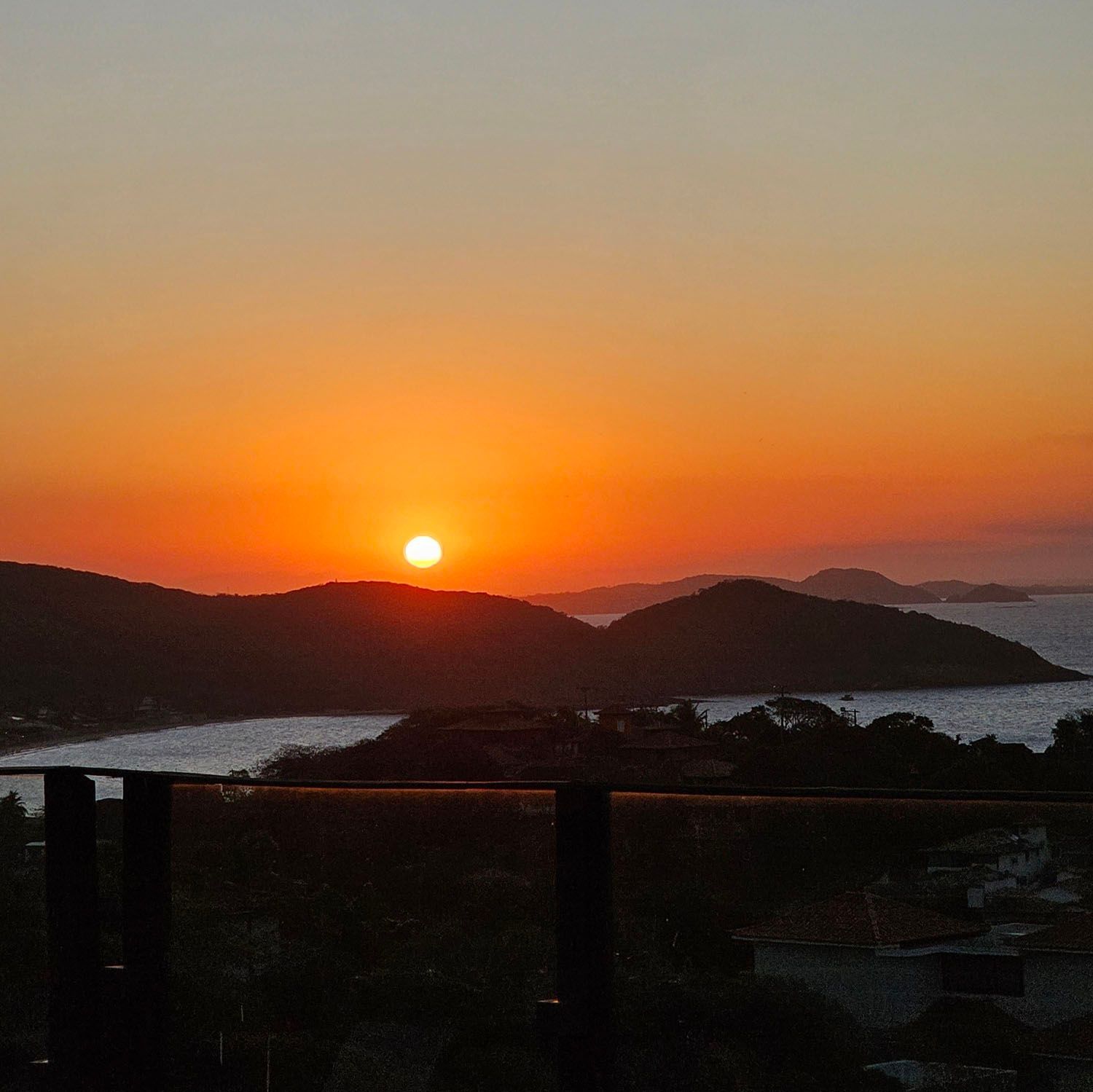Um pôr do sol sobre um corpo de água com montanhas ao fundo