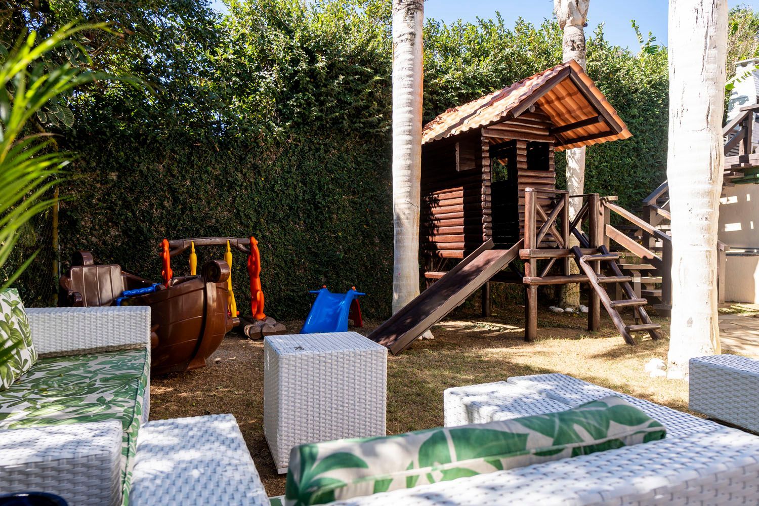 Há um playground no quintal com escorregador e uma casa de madeira.