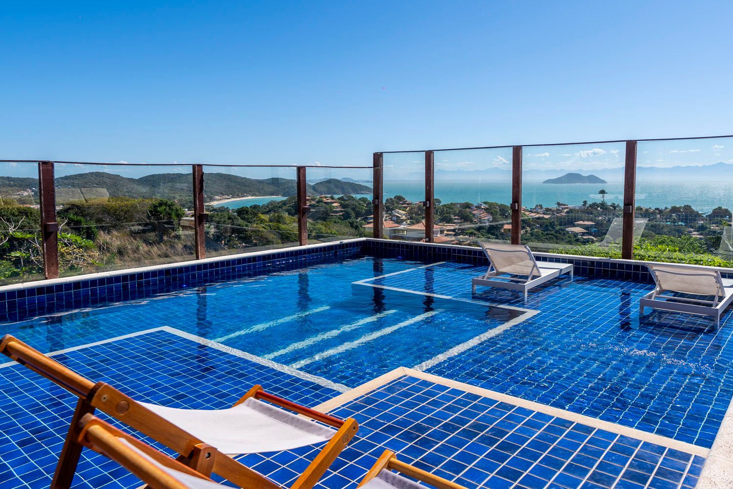 Uma grande piscina com cadeiras e vista para o oceano.