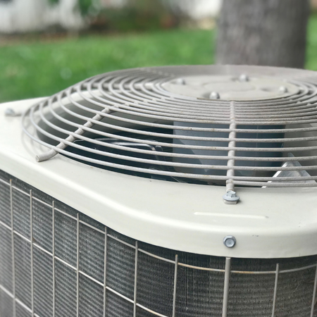 A close up of an air conditioner with a tree in the background