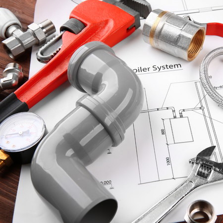 A pipe wrench is laying on top of a drawing of a boiler system