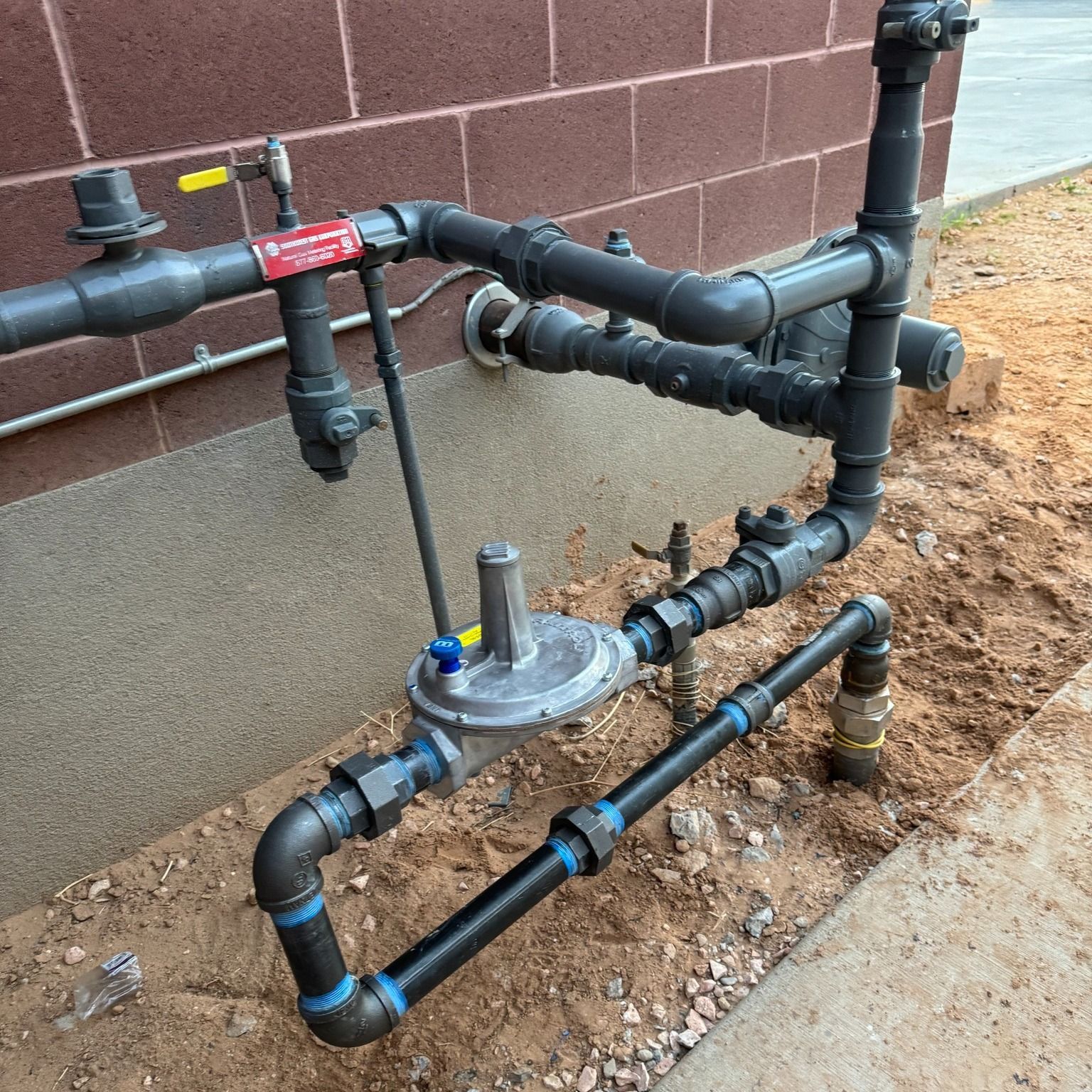 A bunch of pipes are connected to a brick wall