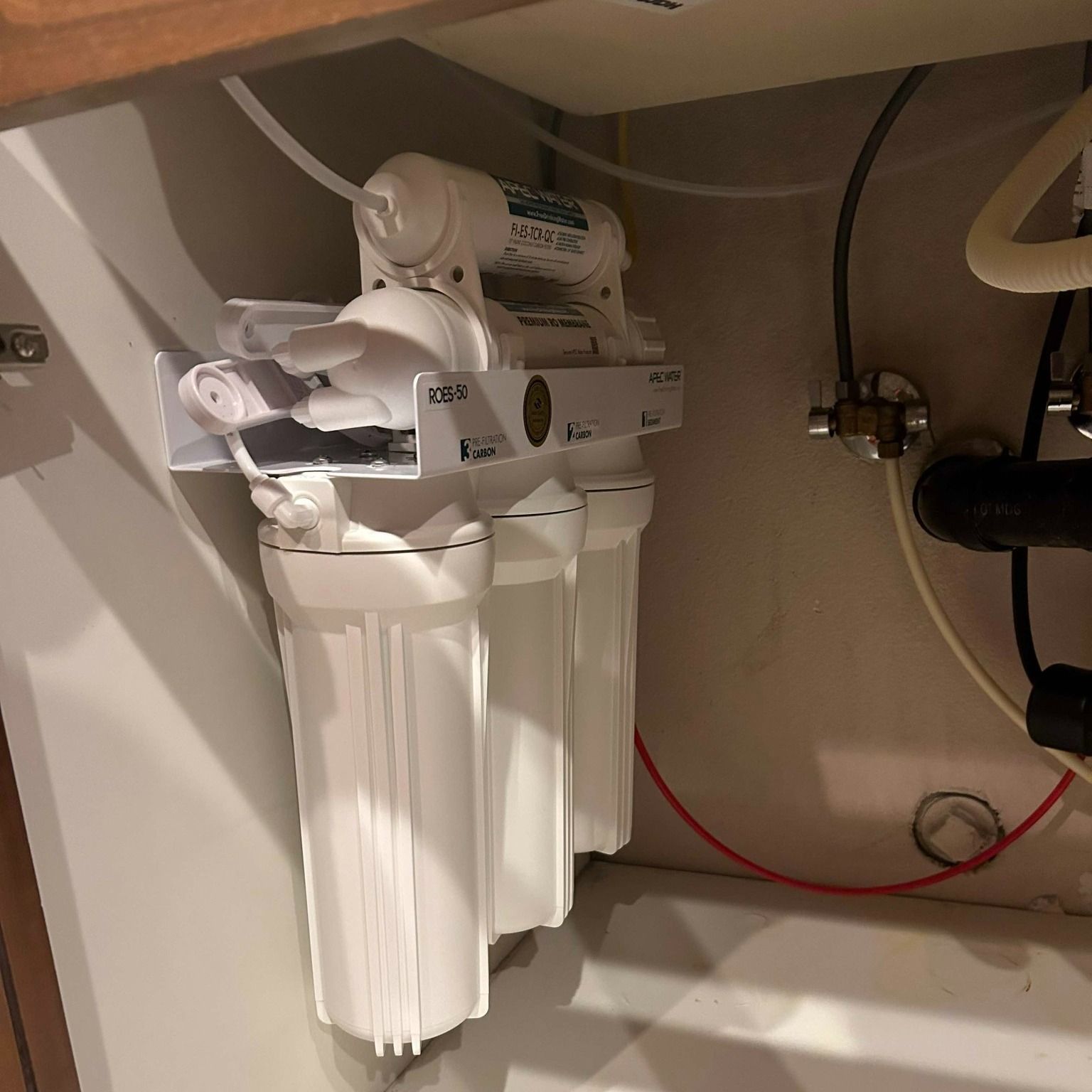 A water filter is under a sink in a kitchen