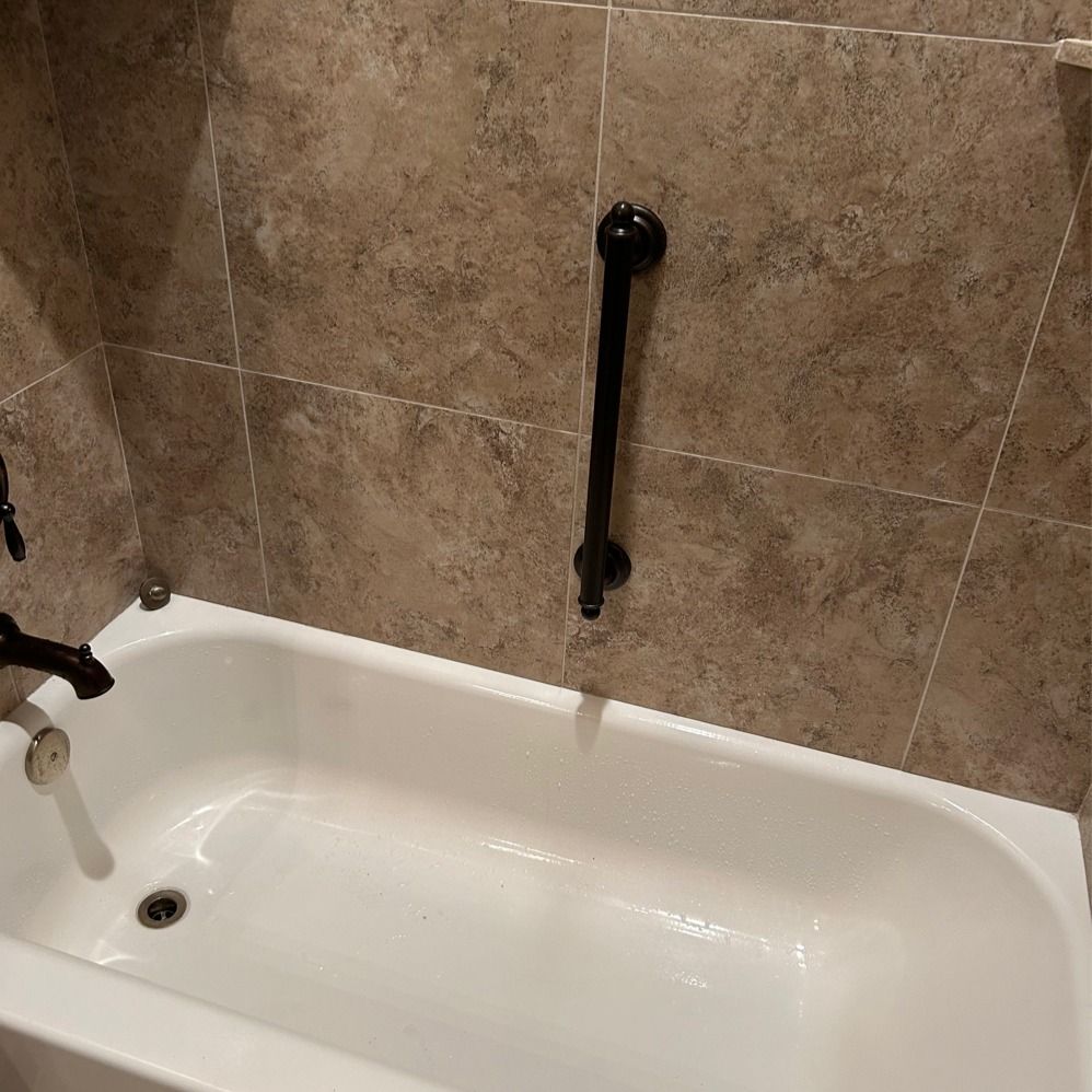 A white bathtub with a black handle on the wall.