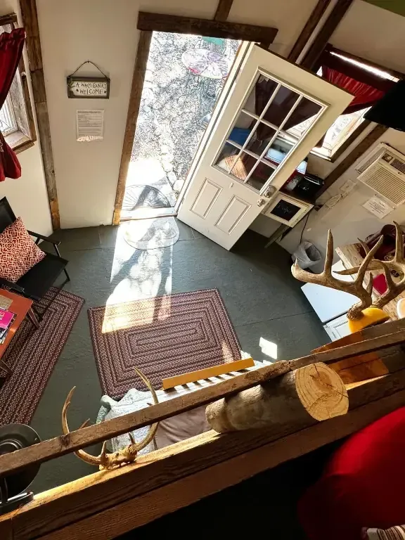 Cozy shop entry with open white door, rug, and sunlit floor by a display counter
