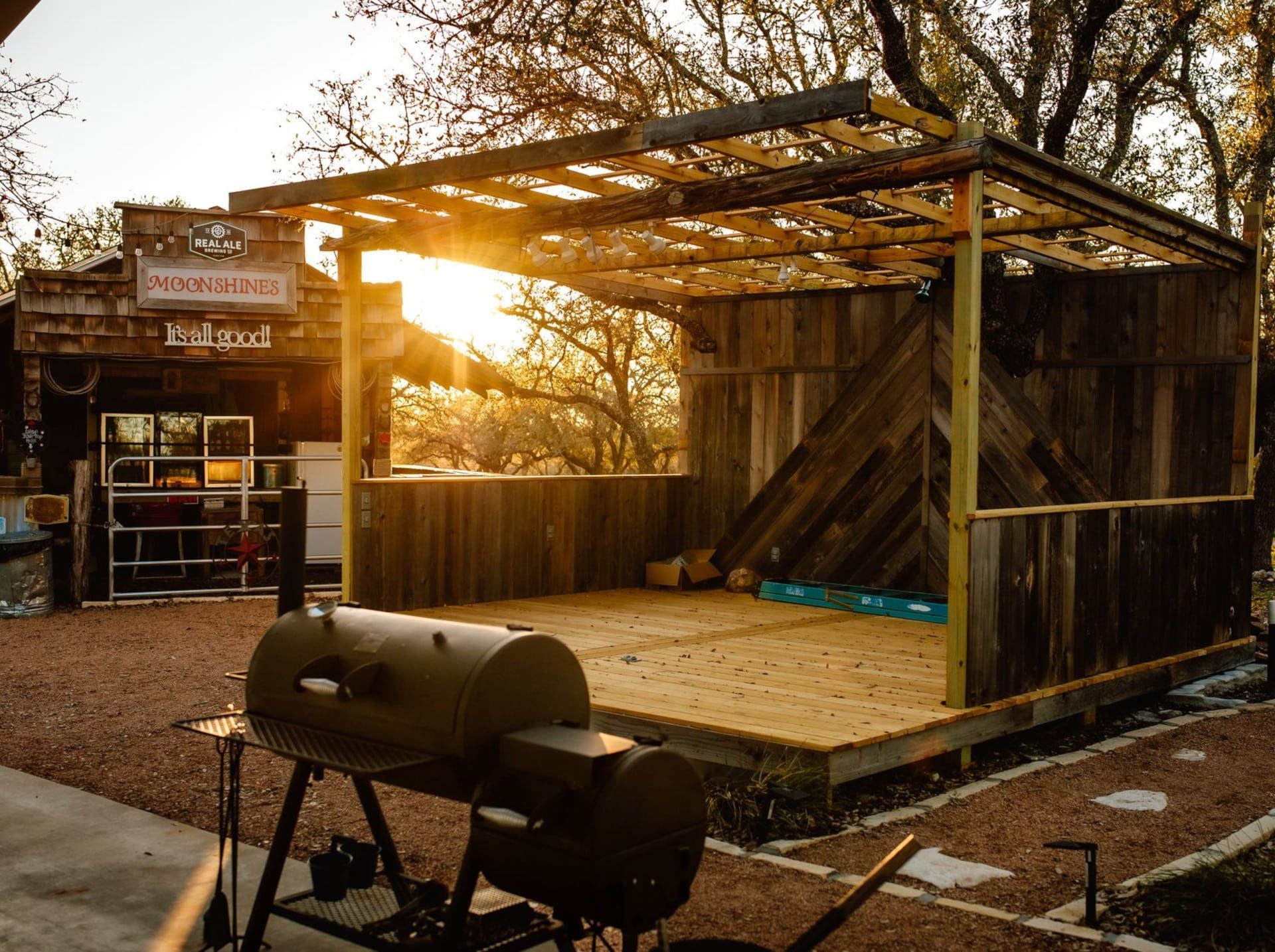 Empty wooden stage with a grill in front, lit by warm sunset light outdoors