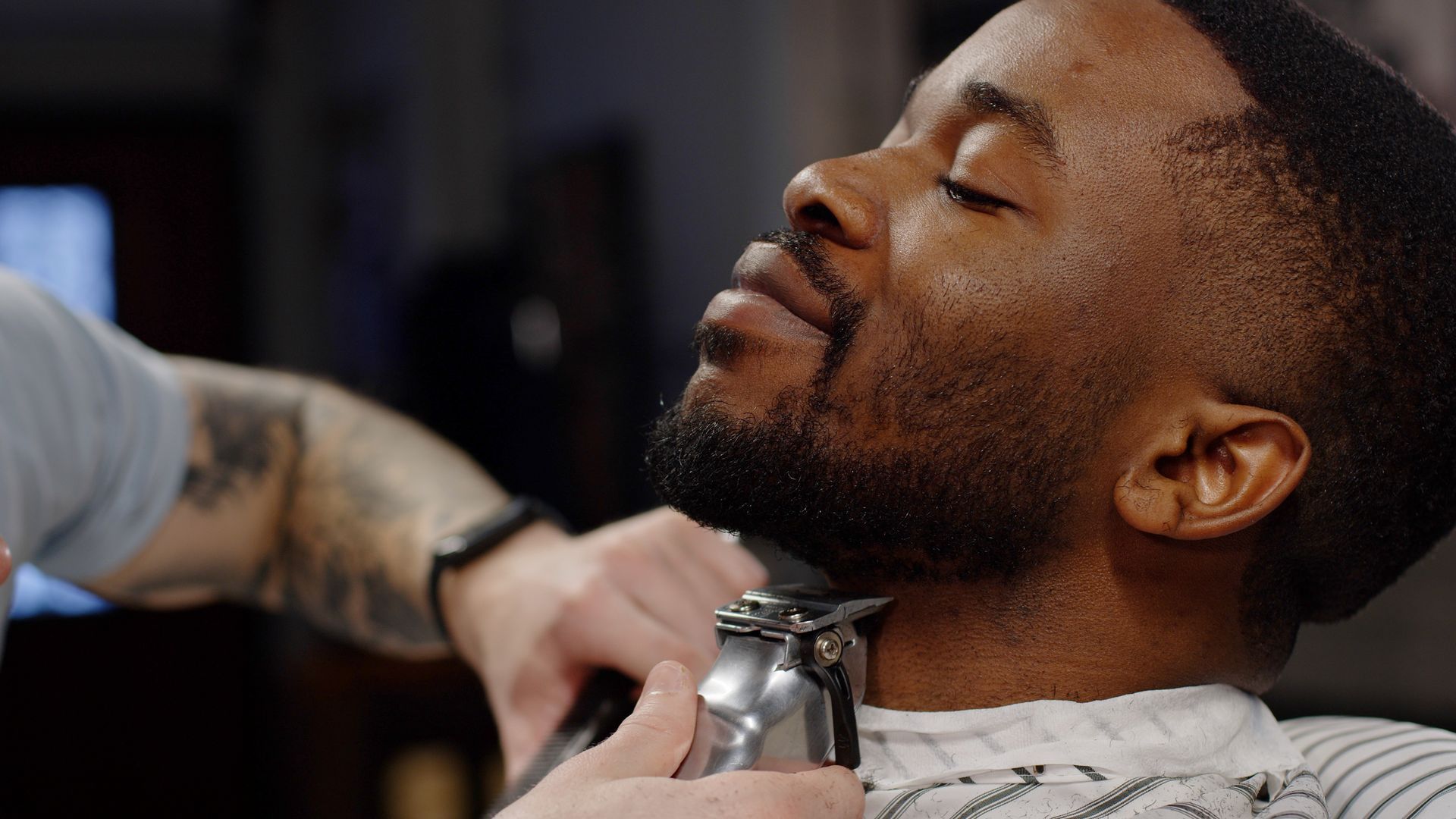 A man is getting his beard trimmed at a barber shop.