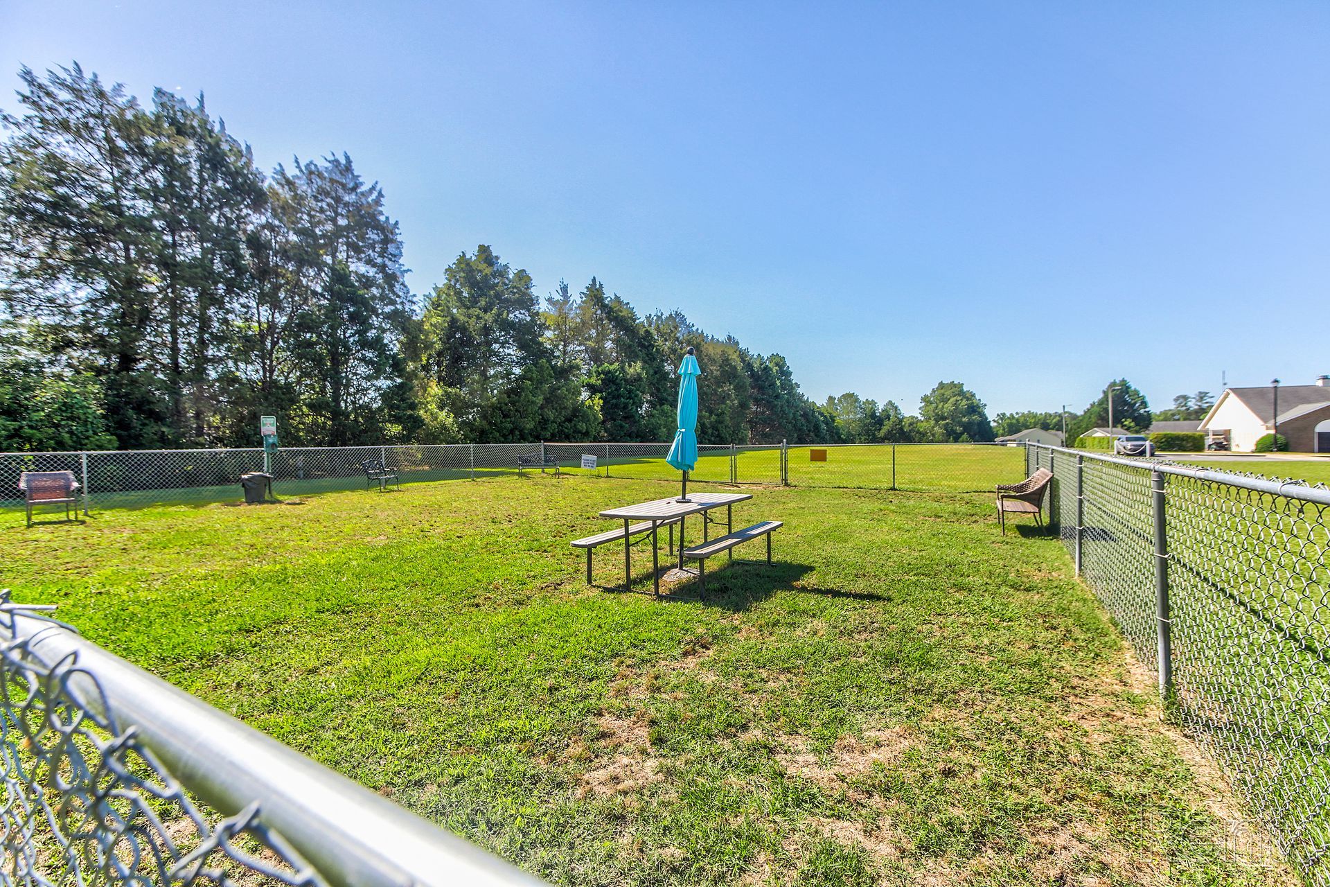 Dog walk park by Meridian Park Clubhouse with picnic bench, umbrella, chairs, and dog toys