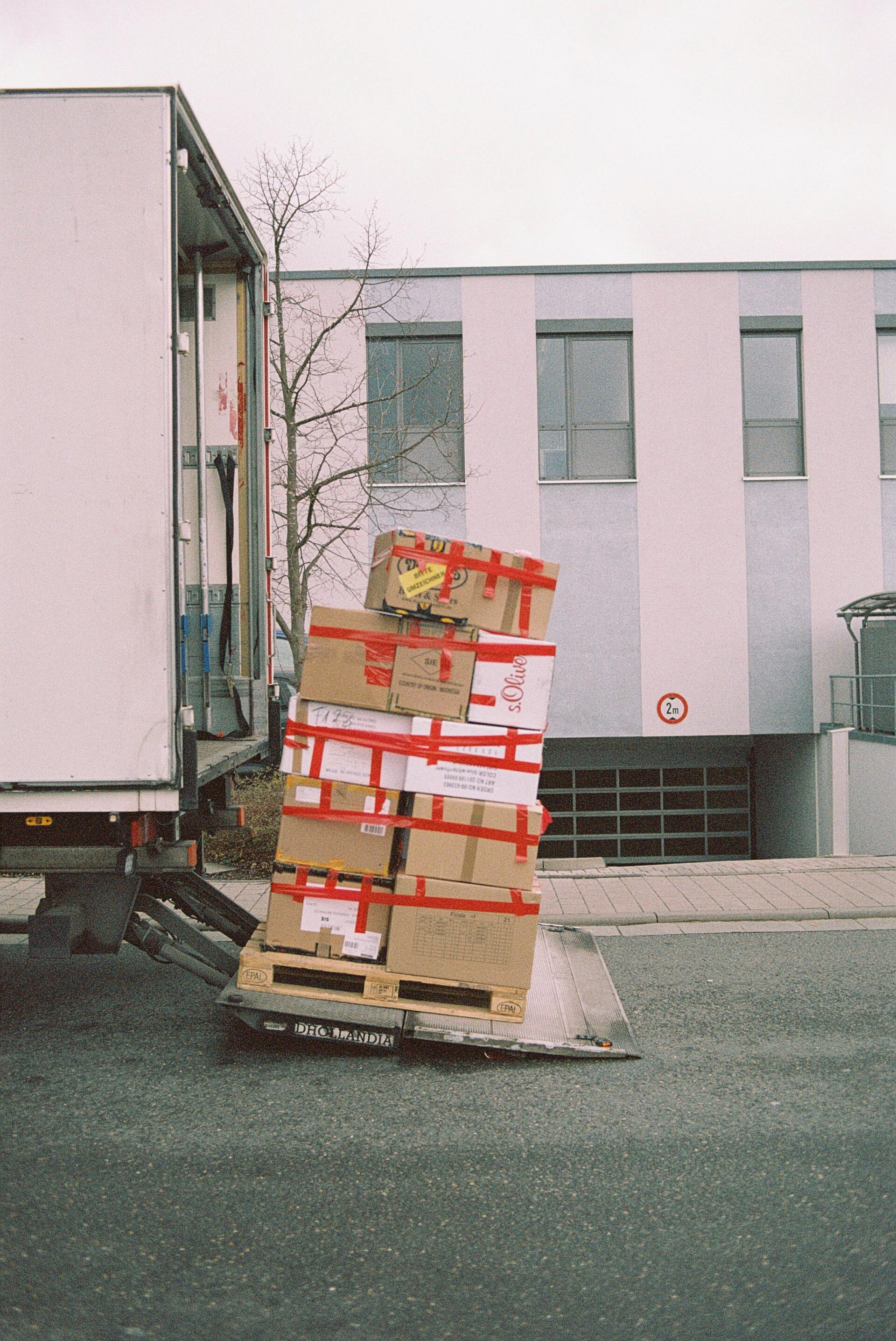 A stack of boxes on a pallet next to a truck