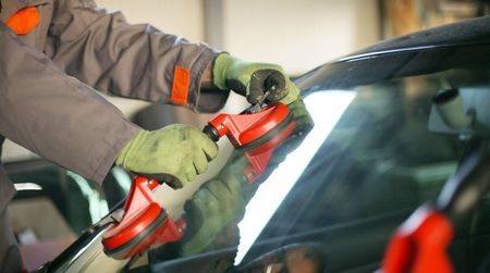 a man is installing a windshield on a car .