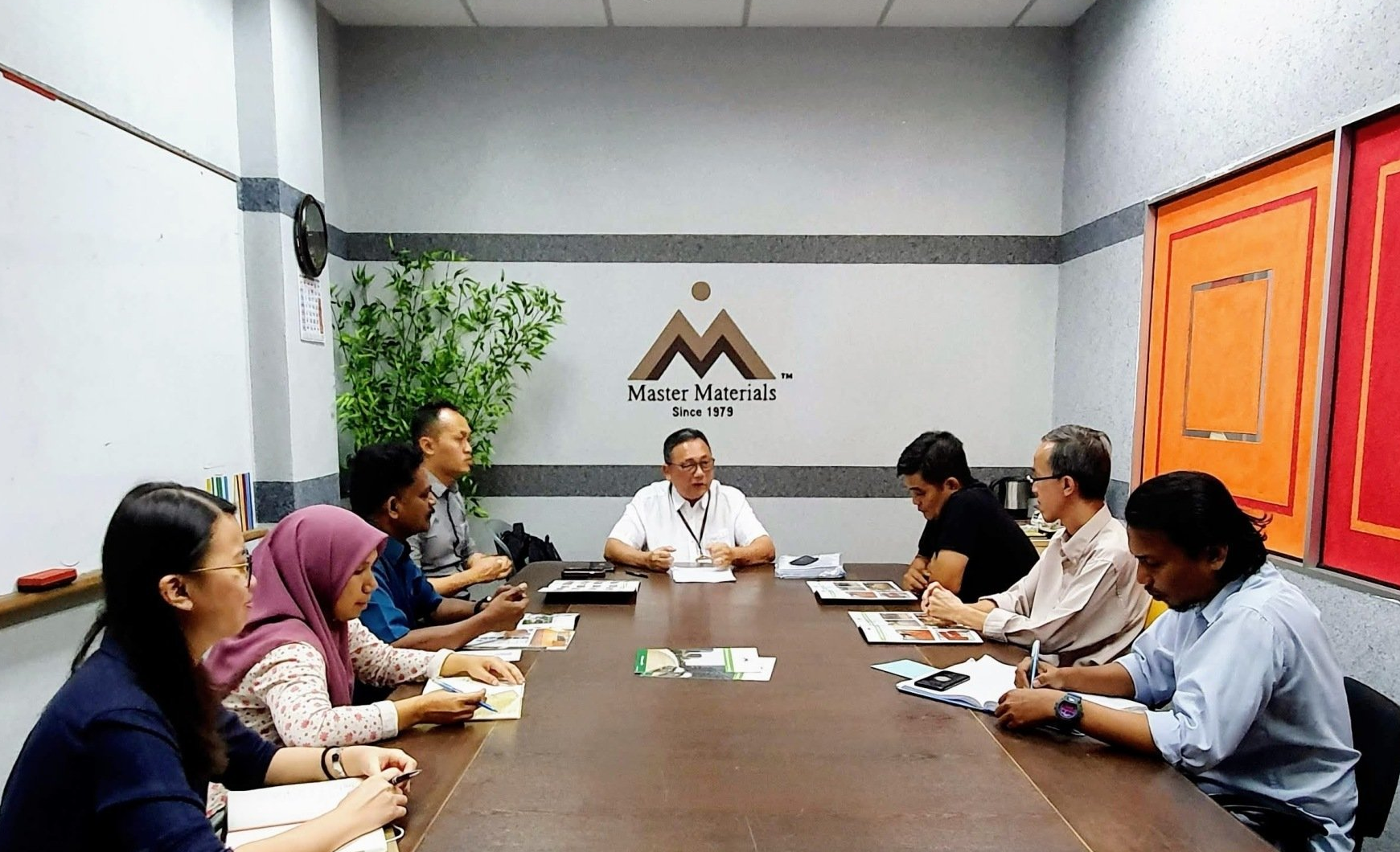 People seated around a conference table in an office, engaged in a meeting.