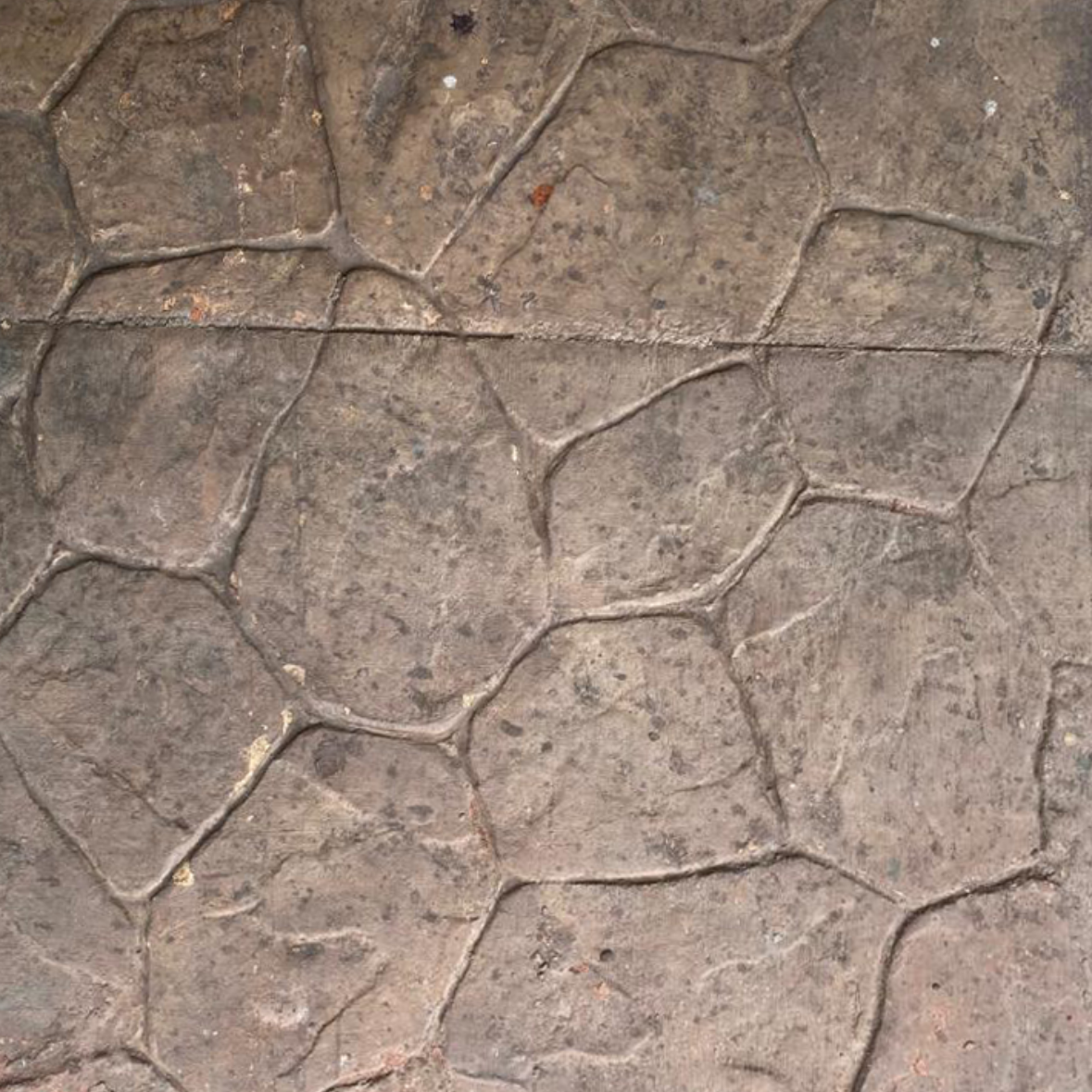Textured concrete surface with irregular stone pattern, gray and brown hues.