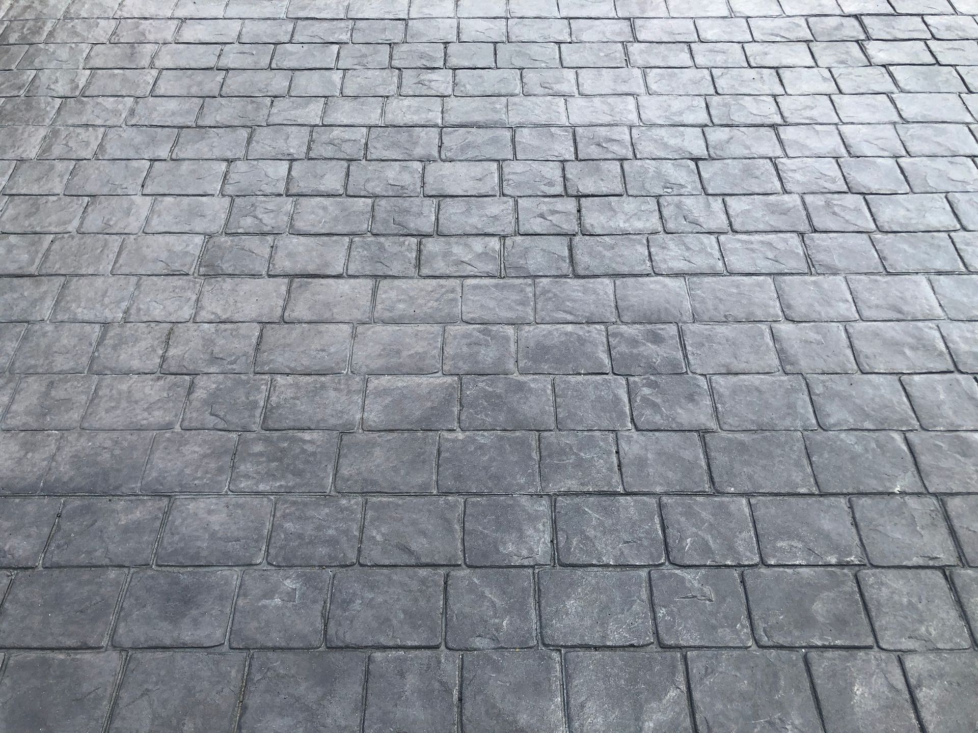 Gray stamped concrete, textured to resemble cobblestones, covering a surface.