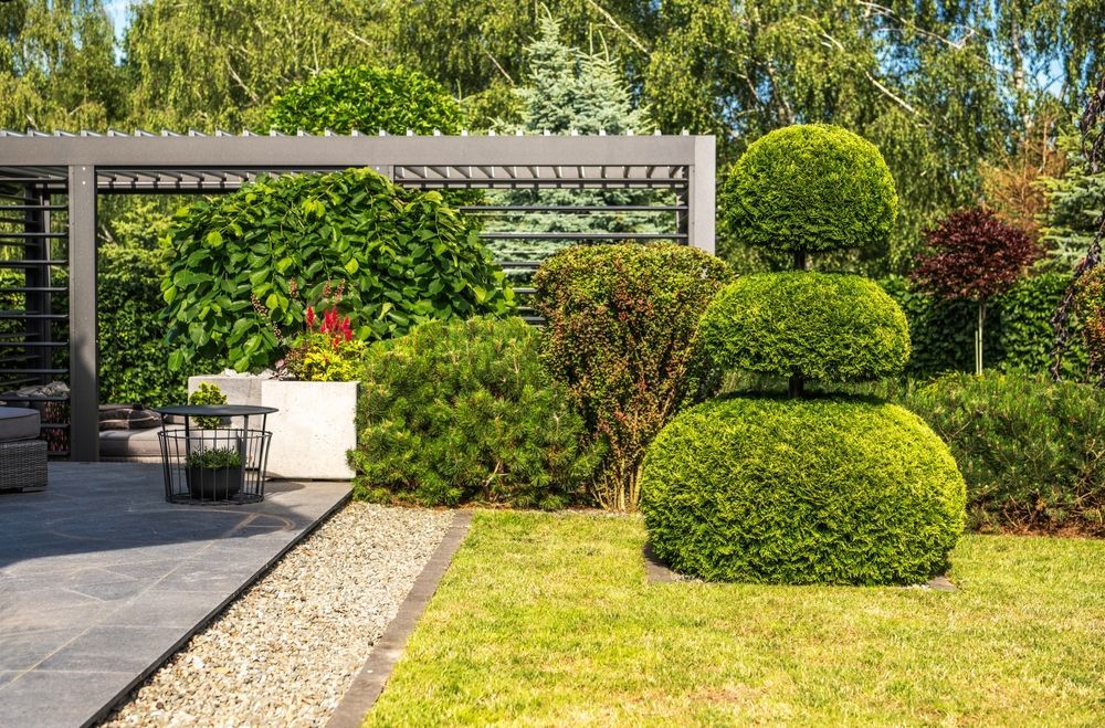 A lush green garden with a pergola and a table and chairs.