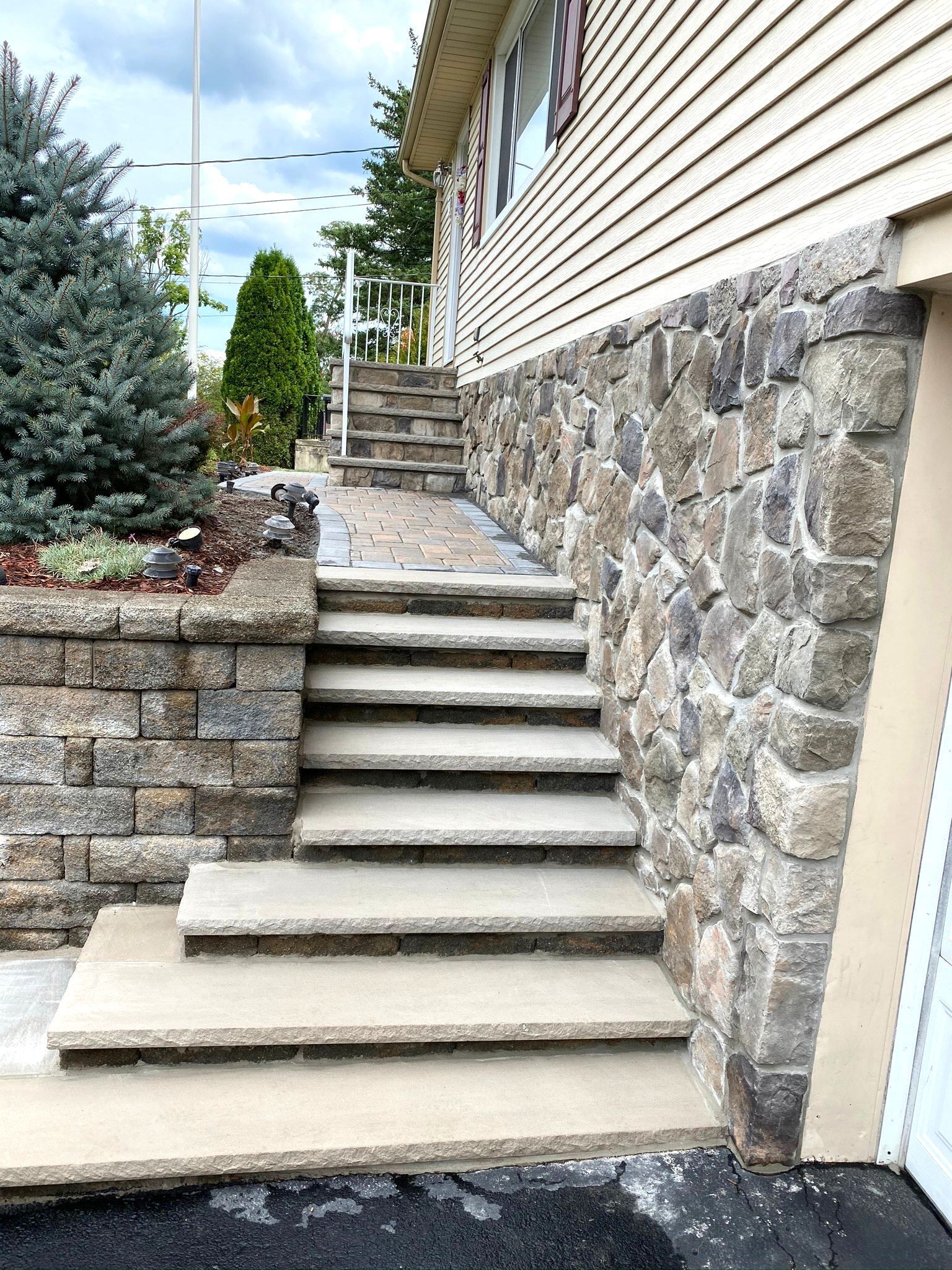 A stone wall with stairs leading up to a house.