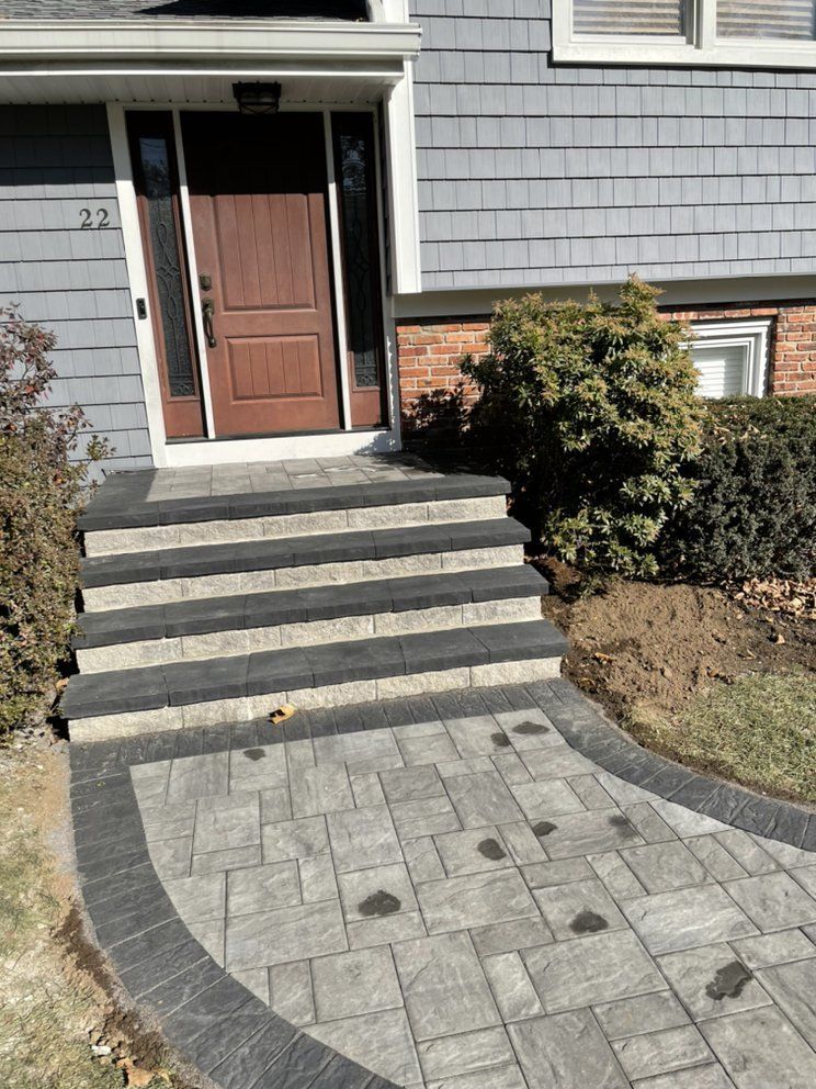 A brick walkway leading to stairs in front of a house.