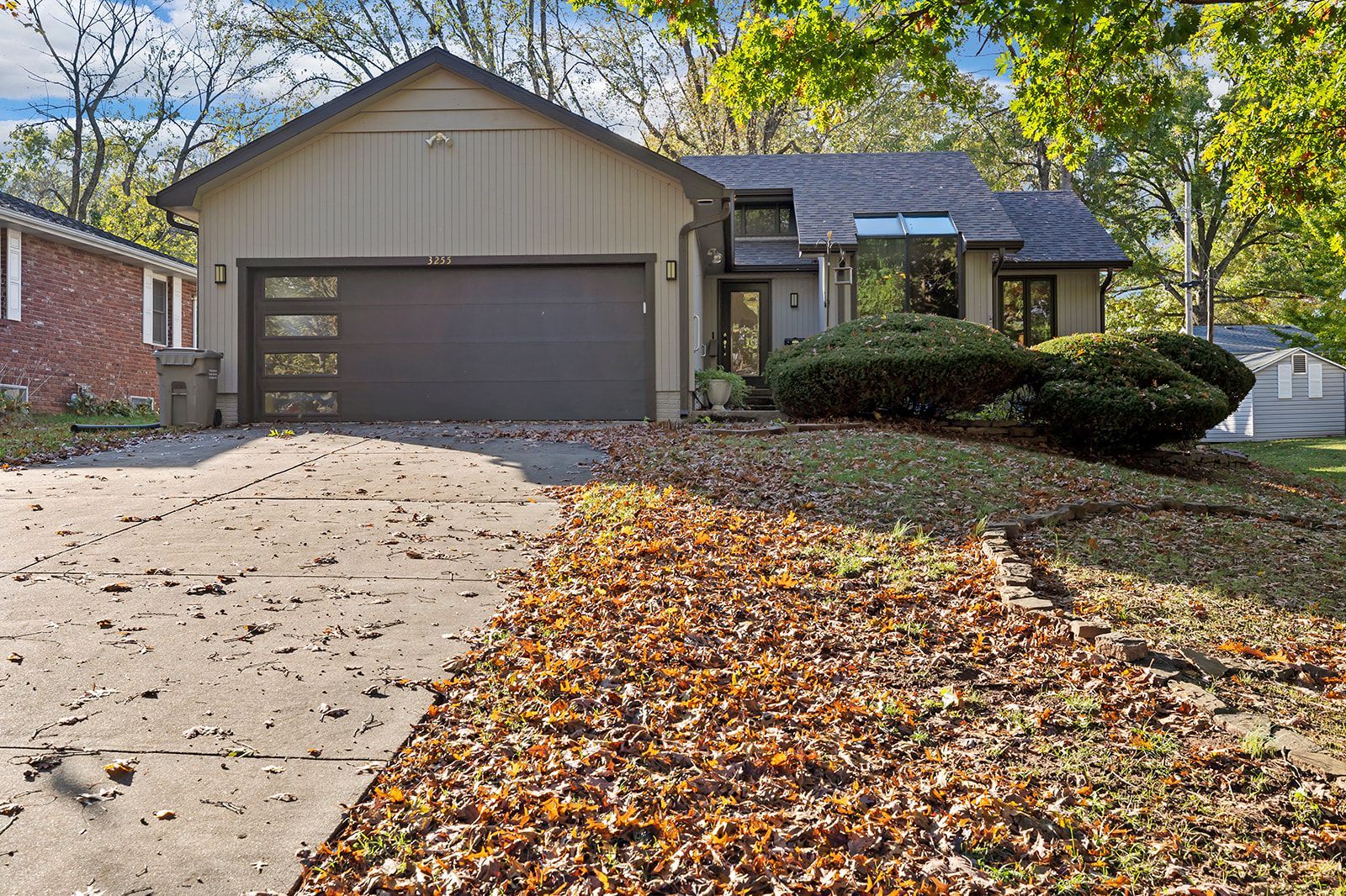 A house with a garage and a driveway covered in leaves.