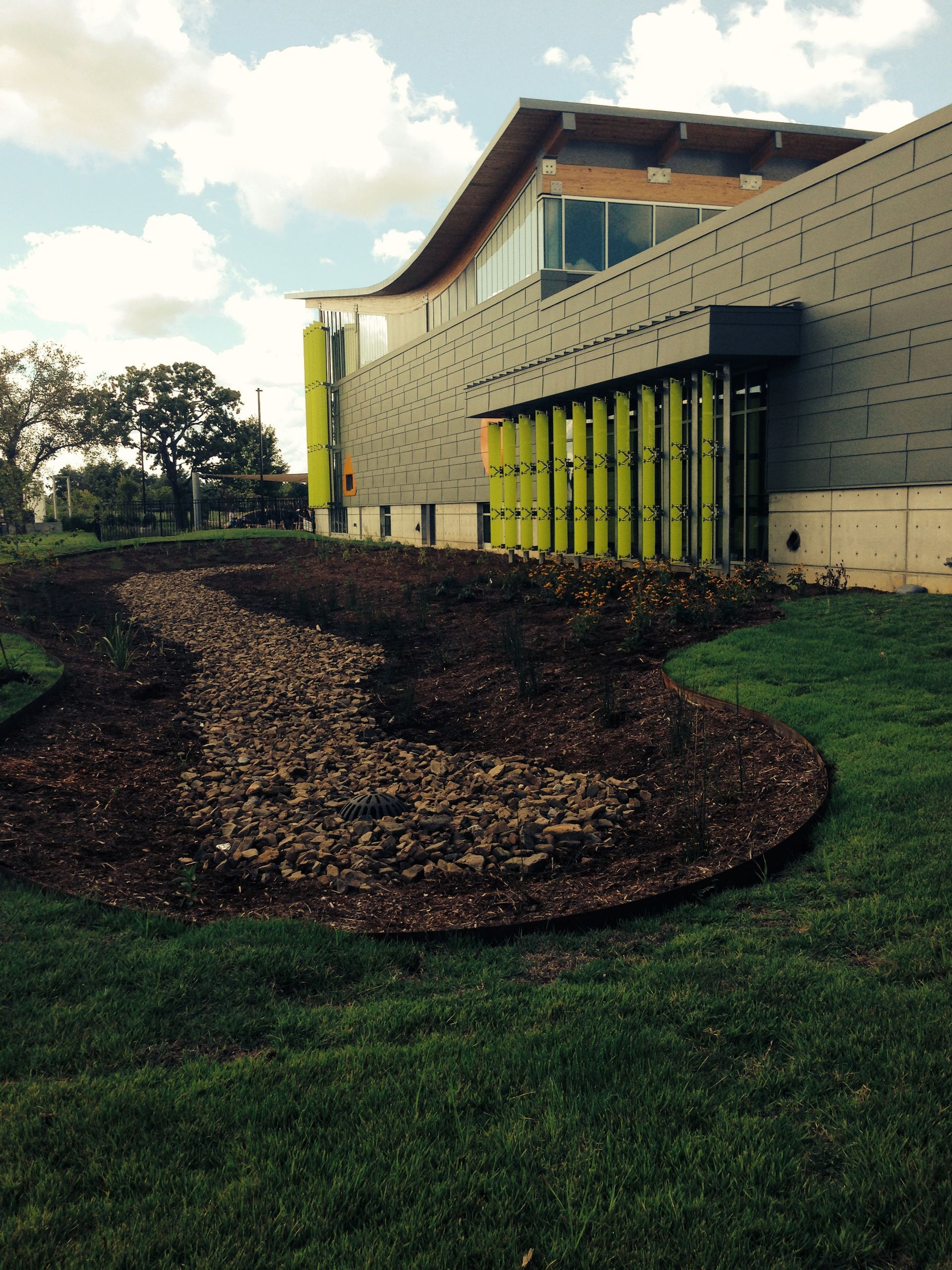 A large building with a lot of windows is surrounded by a lush green field