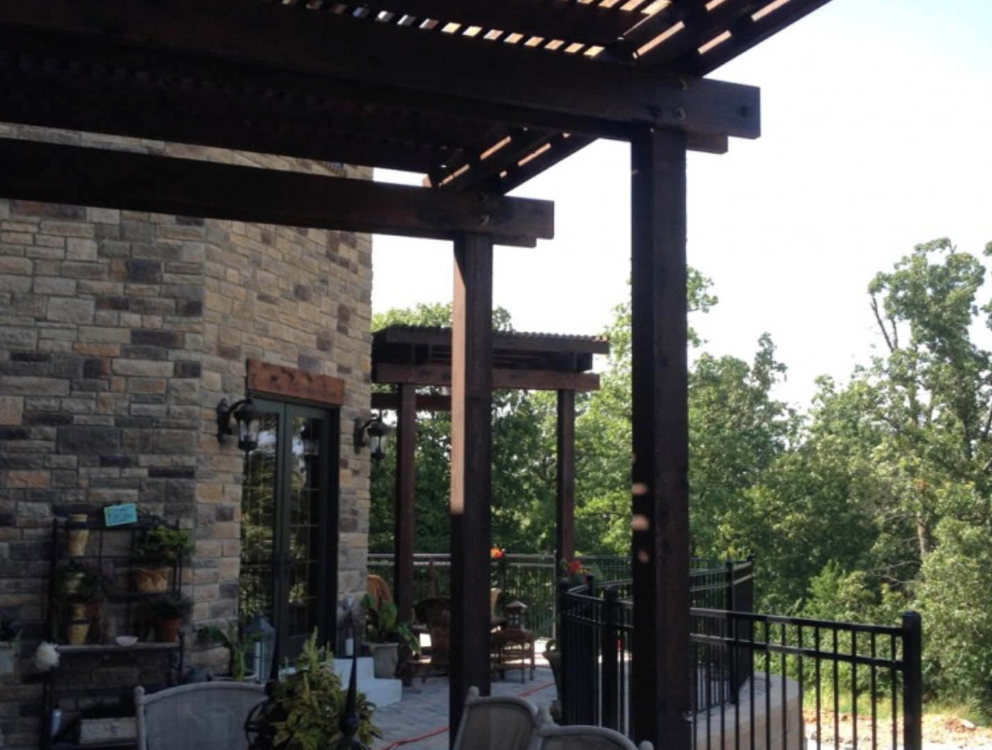 A patio with a pergola and chairs in front of a stone building