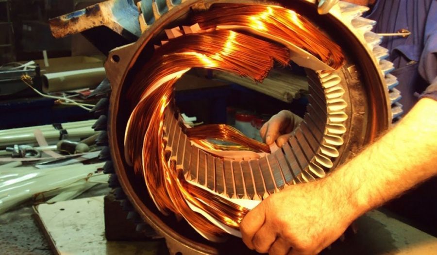 Un hombre está trabajando en un motor eléctrico con cables de cobre.