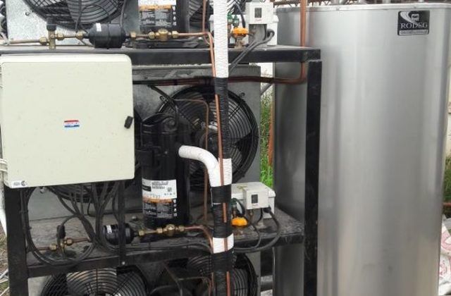 Un calentador de agua de acero inoxidable está colocado encima de un estante de metal.