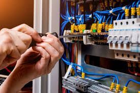 Un electricista está trabajando en una caja eléctrica con un destornillador.