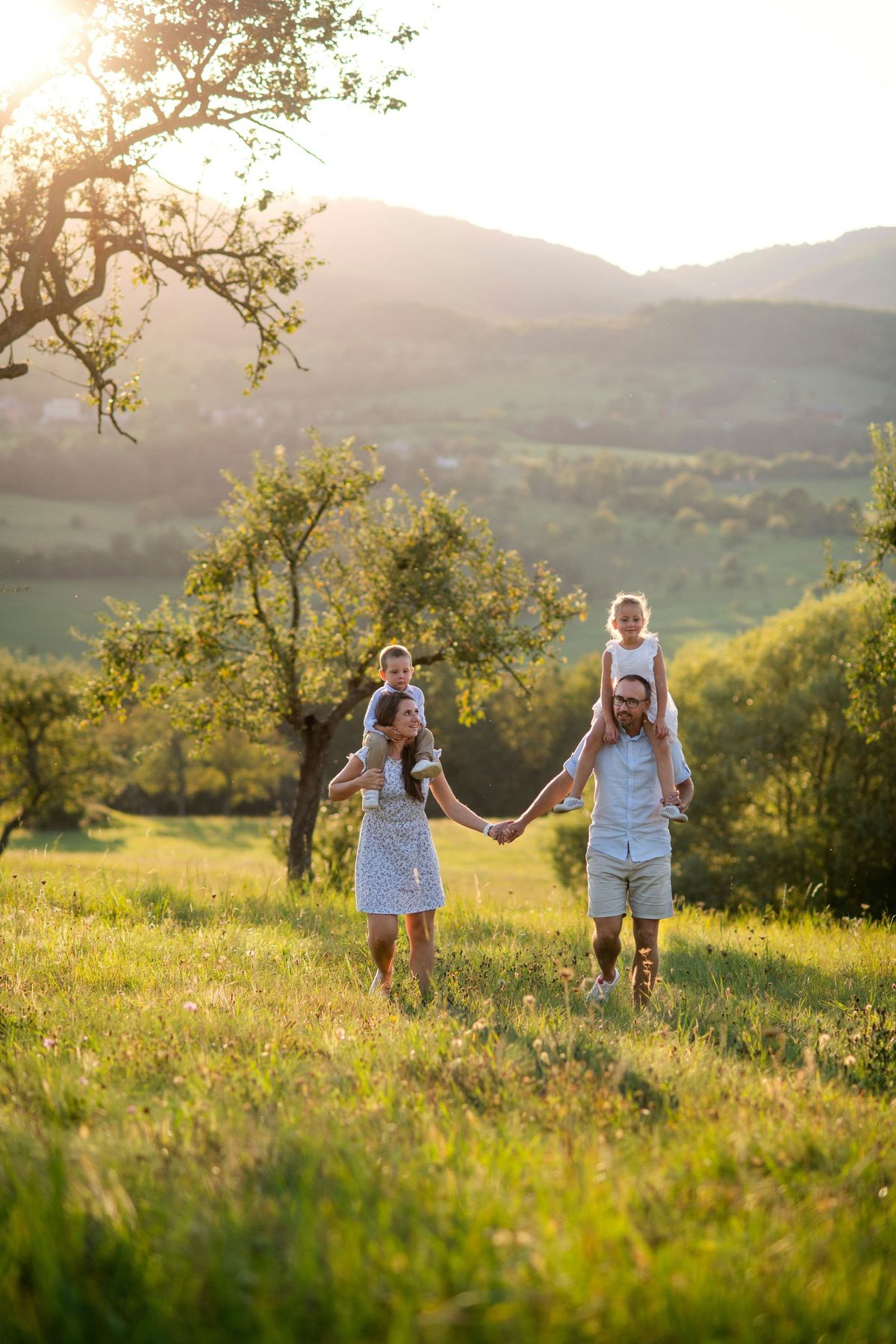 A family is walking through a grassy field holding hands.