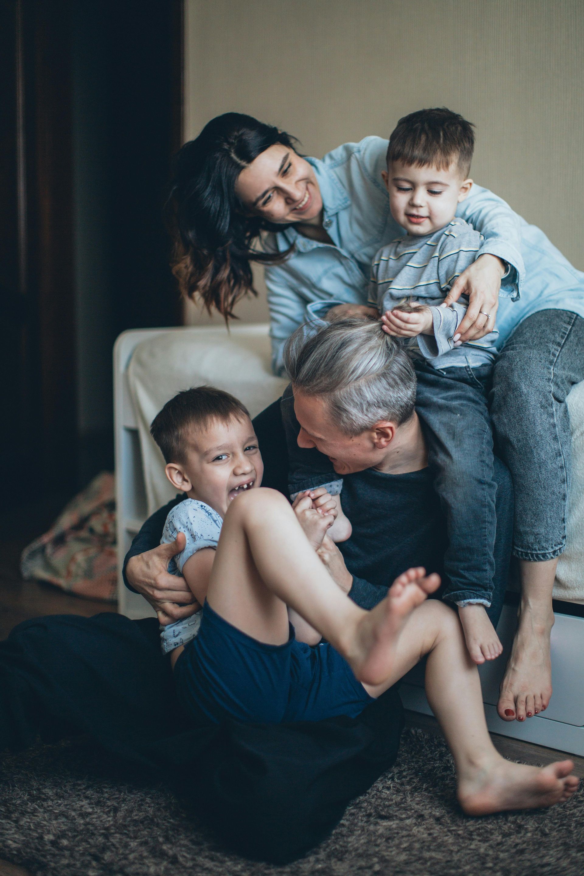 A family is sitting on a couch playing with their children.