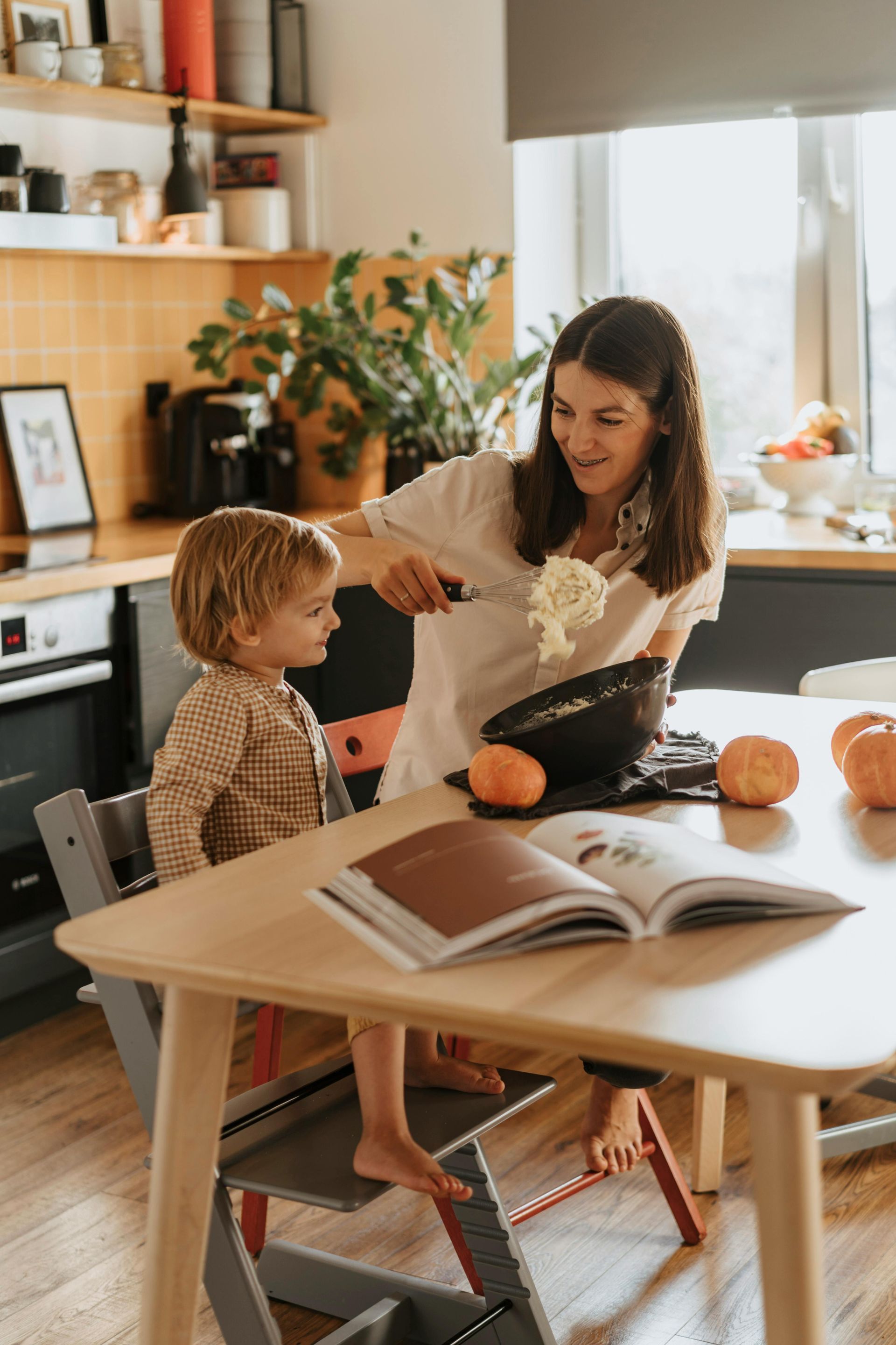 A woman and a child are sitting at a table in a kitchen.