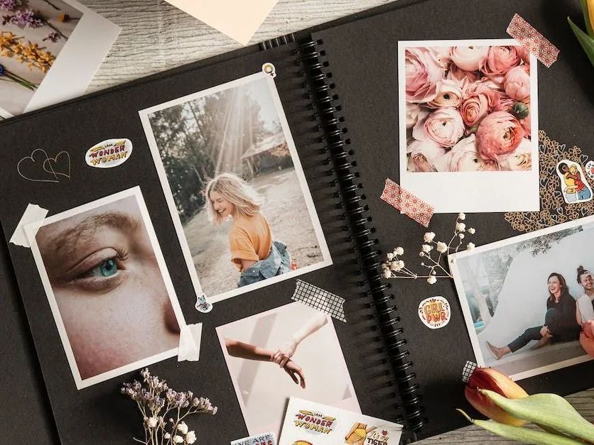 A spiral bound photo album filled with pictures and stickers on a table.