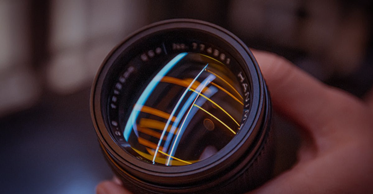 A person is holding a camera lens in their hand.