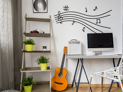 A guitar is sitting on a desk next to a computer.