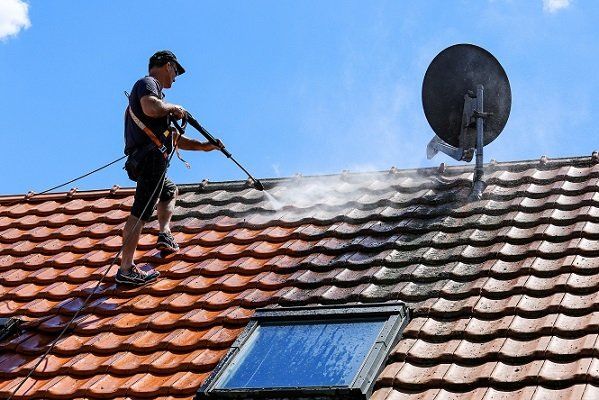 A roofer cleaning the roof with high pressure water jet in Wollongong, NSW.