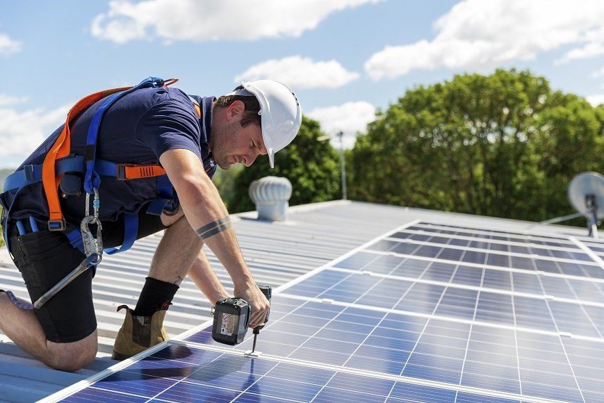 A roofing contractor fixing the solar panel on top of a residential roof in Wollongong, NSW.
