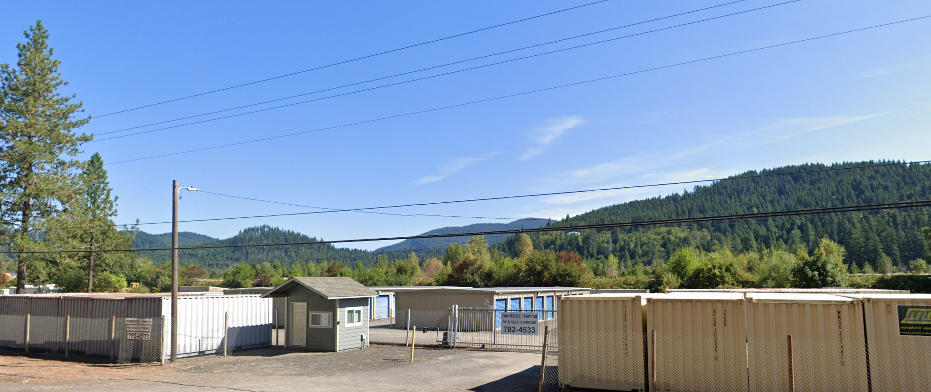 Fenced storage facility with small office, mountains, and blue sky in the background.