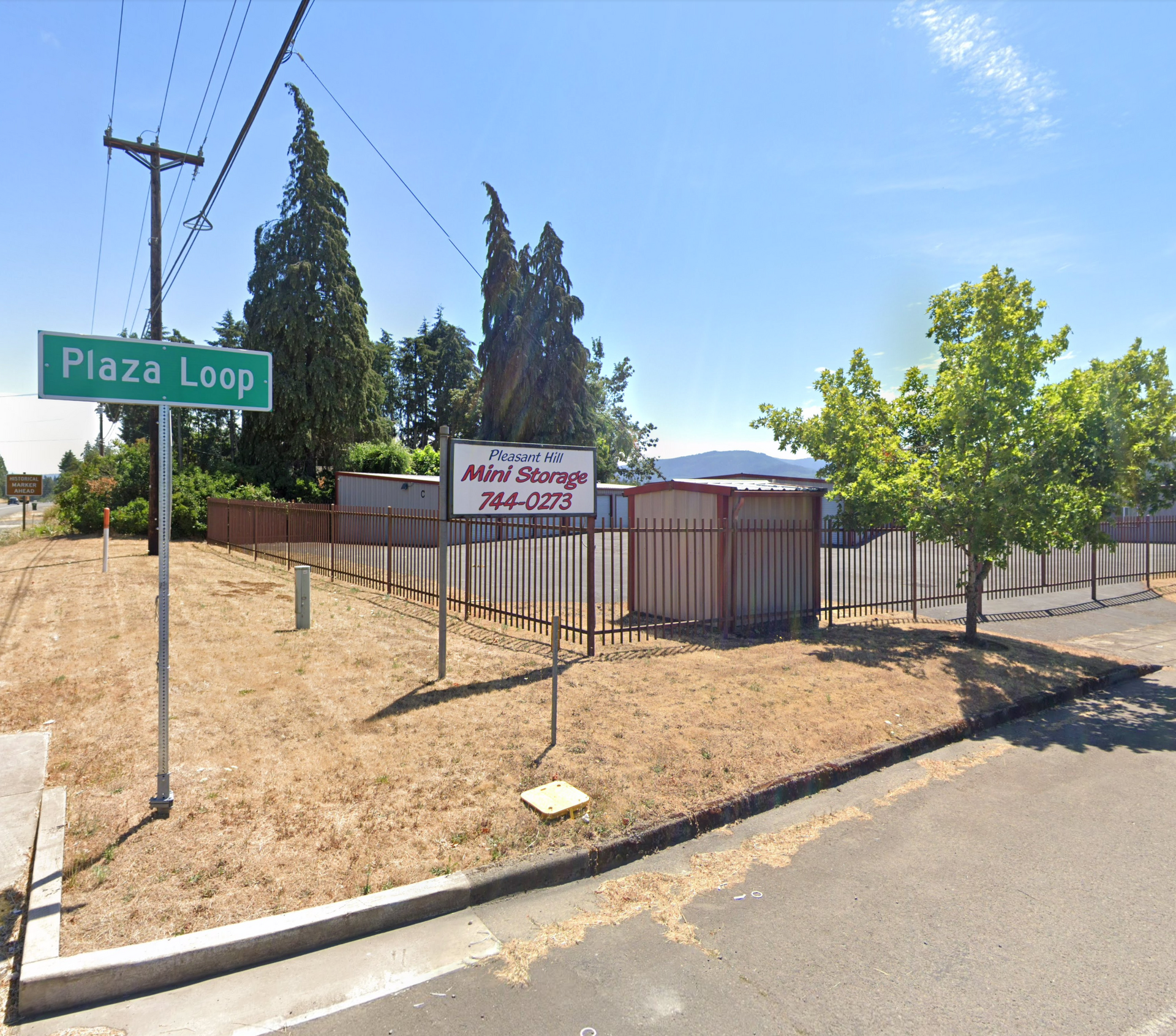 Self-storage facility at the corner of Plaza Loop street on a sunny day. Sign says 