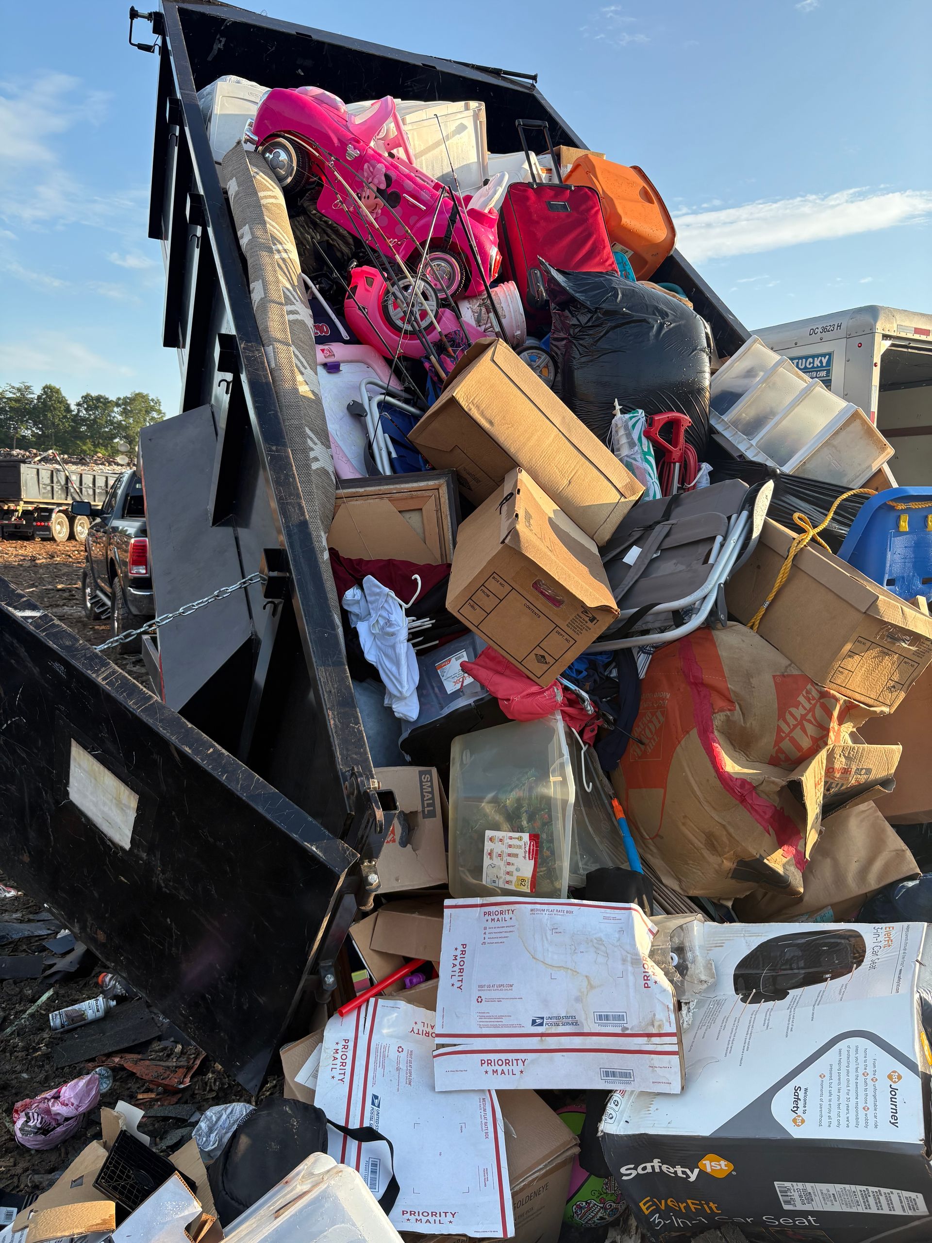 Dumpster overflowing with boxes, bags, and miscellaneous items, outdoors.