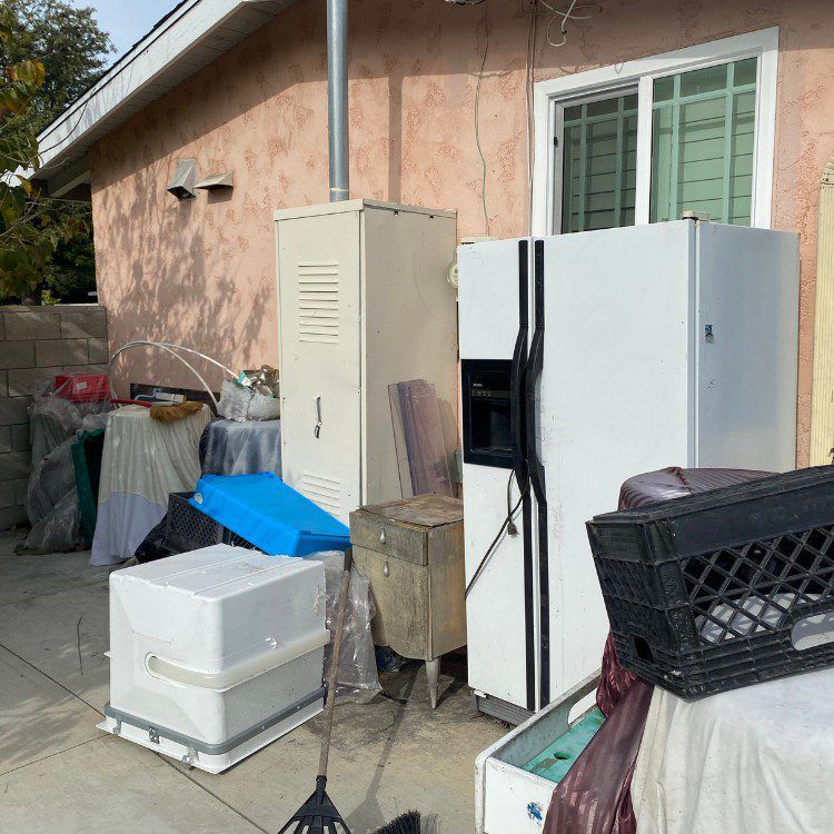 Backyard with appliances, miscellaneous items, and a tan stucco wall.