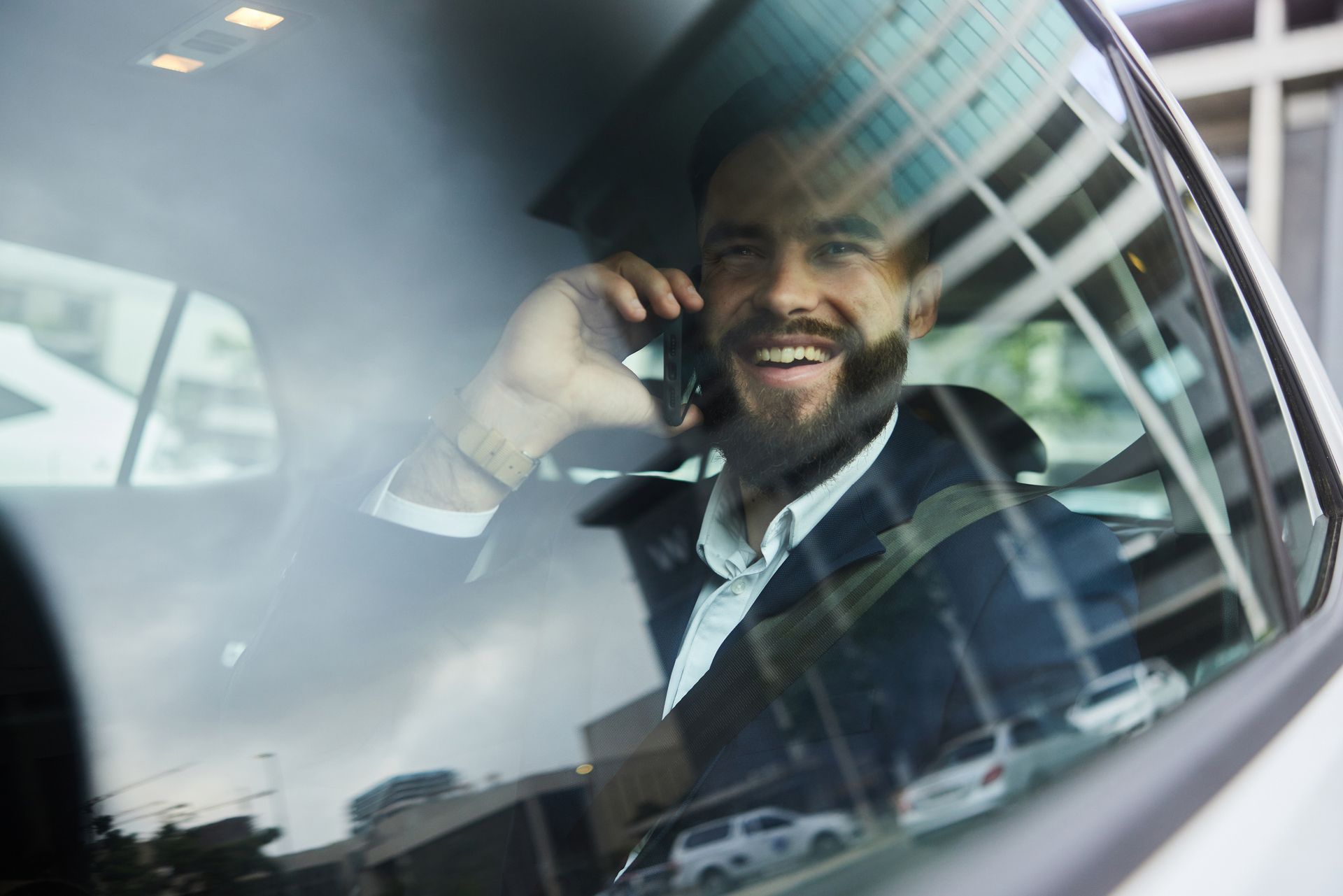 A man is sitting in a car talking on a cell phone.