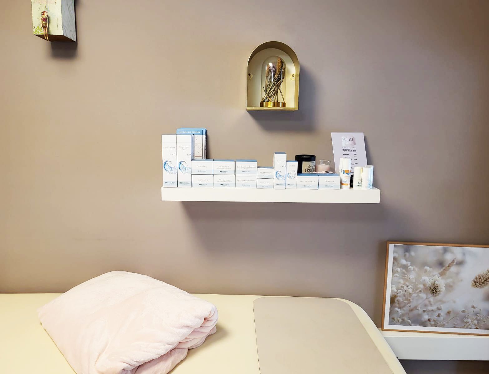 Ein Bett mit einem Handtuch und einem Regal mit Kosmetika darauf.