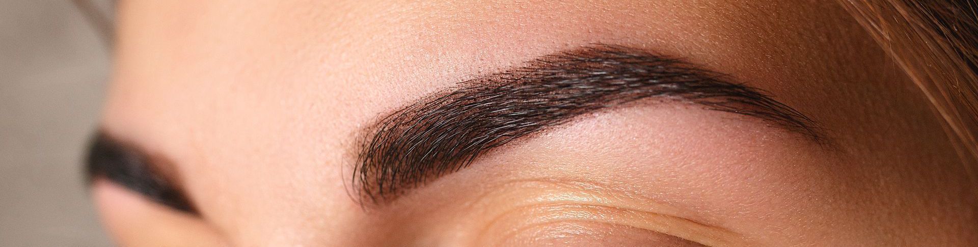 Eine Nahaufnahme der geschminkten Augenbrauen einer Frau.