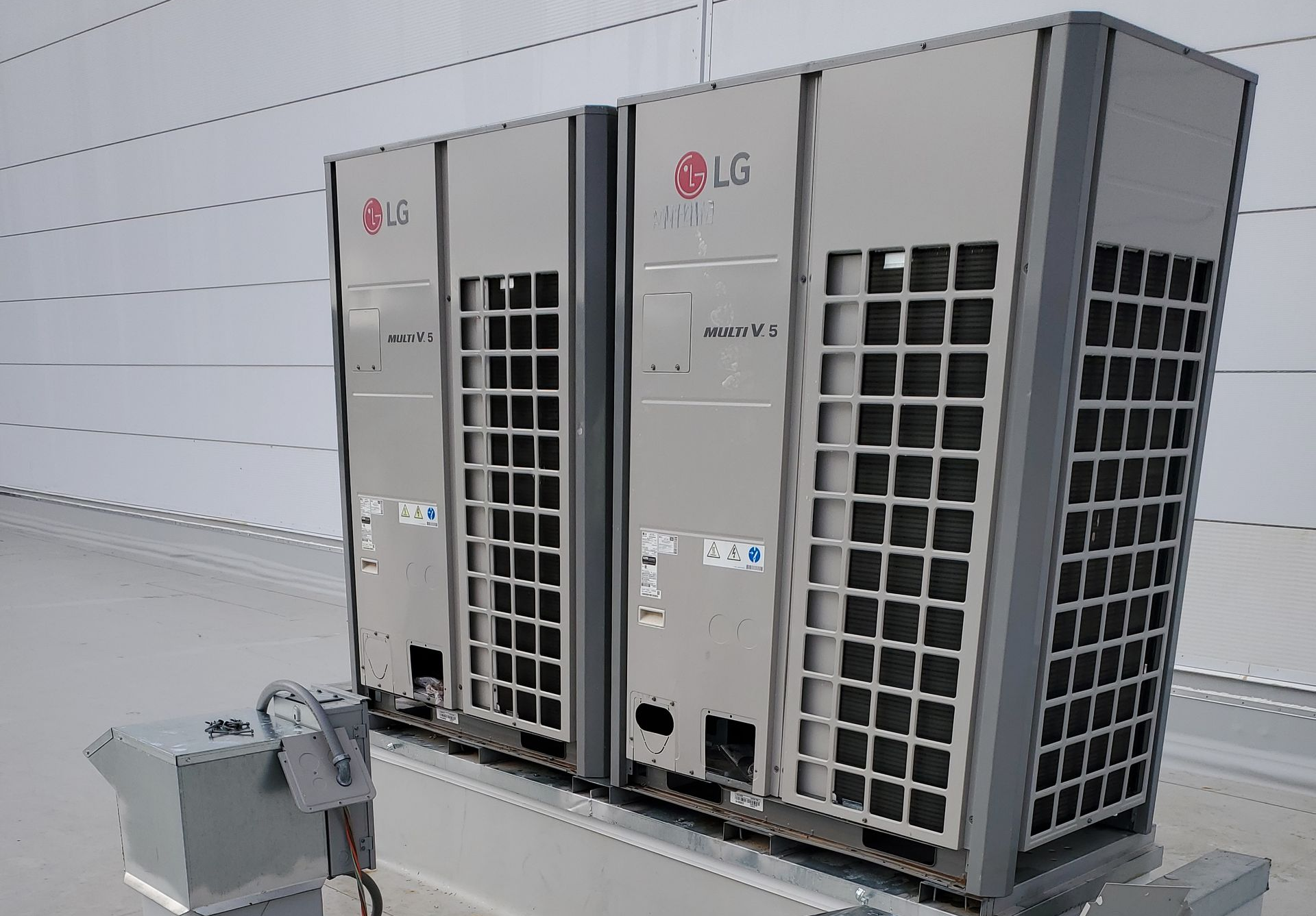 Two LG air conditioning units on a rooftop. Gray metal boxes with vents.