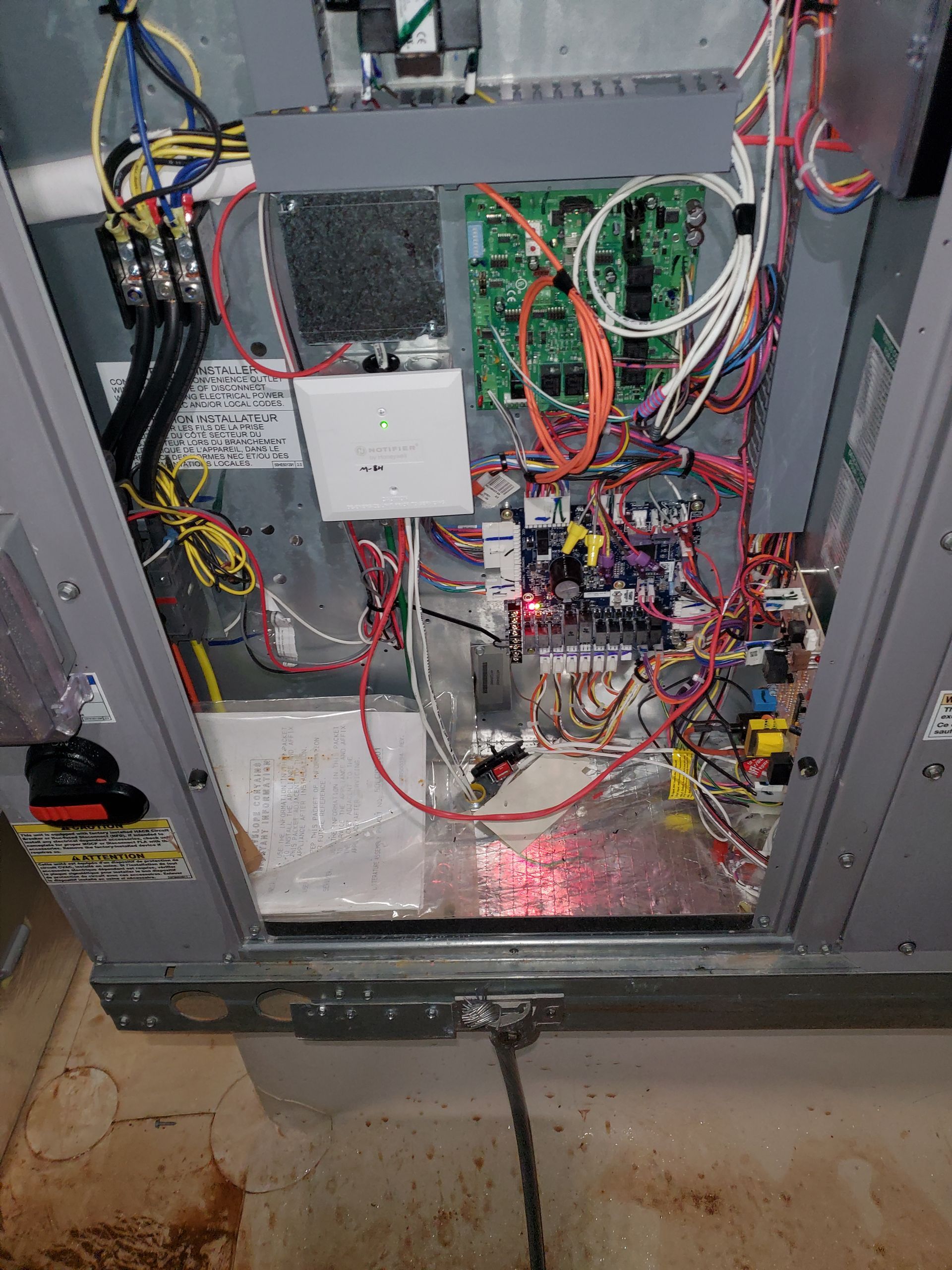 Open view of air handler unit's electrical components with wires and circuit boards, indoors.