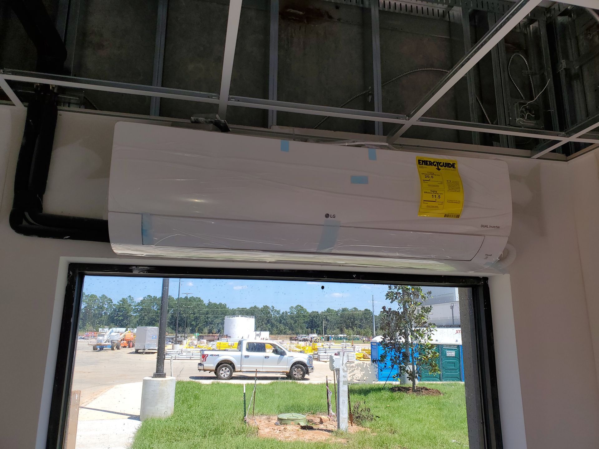 An air conditioner unit is mounted above a window in a room under construction.