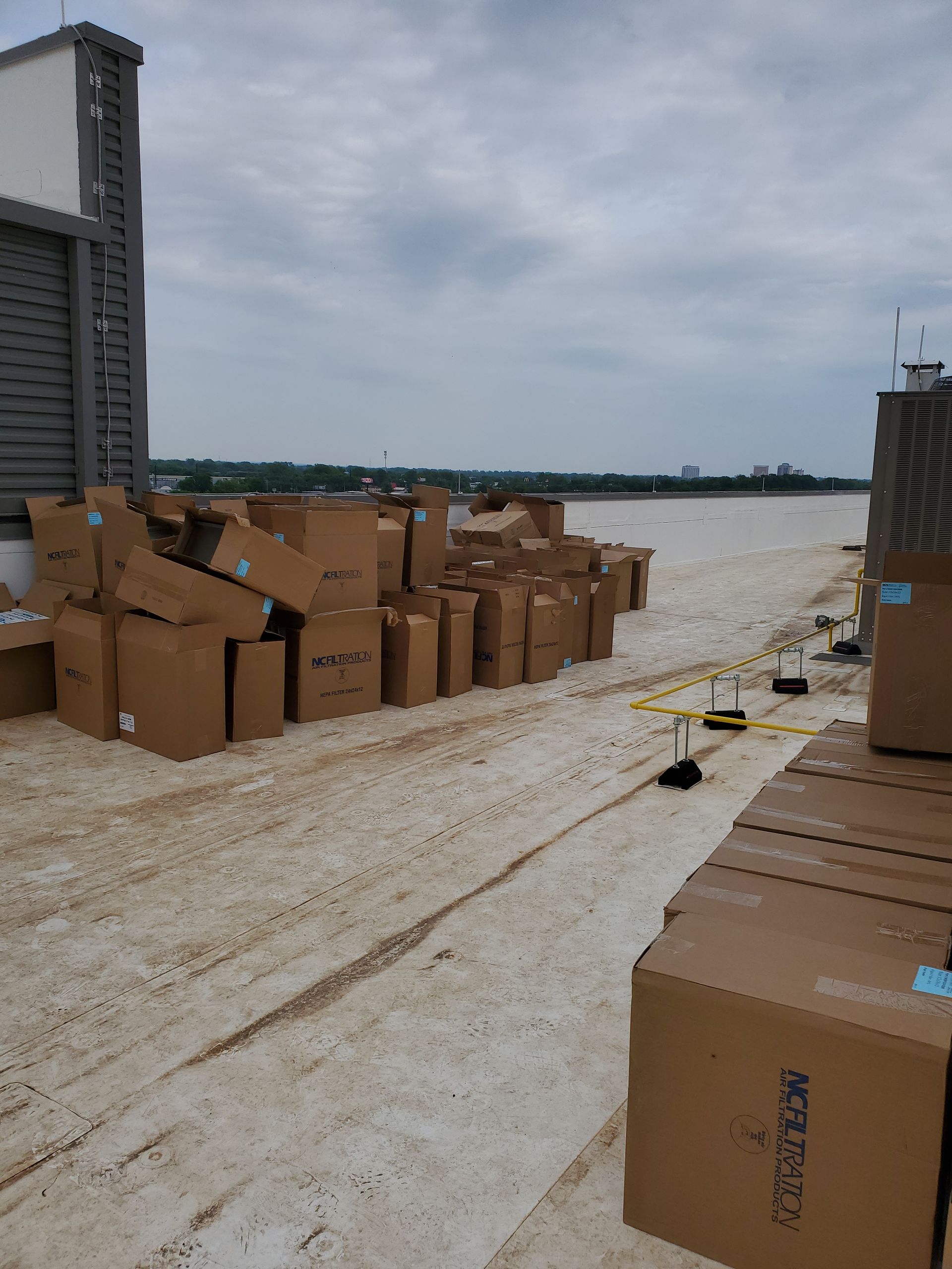 Cardboard boxes piled on a rooftop, overcast sky.
