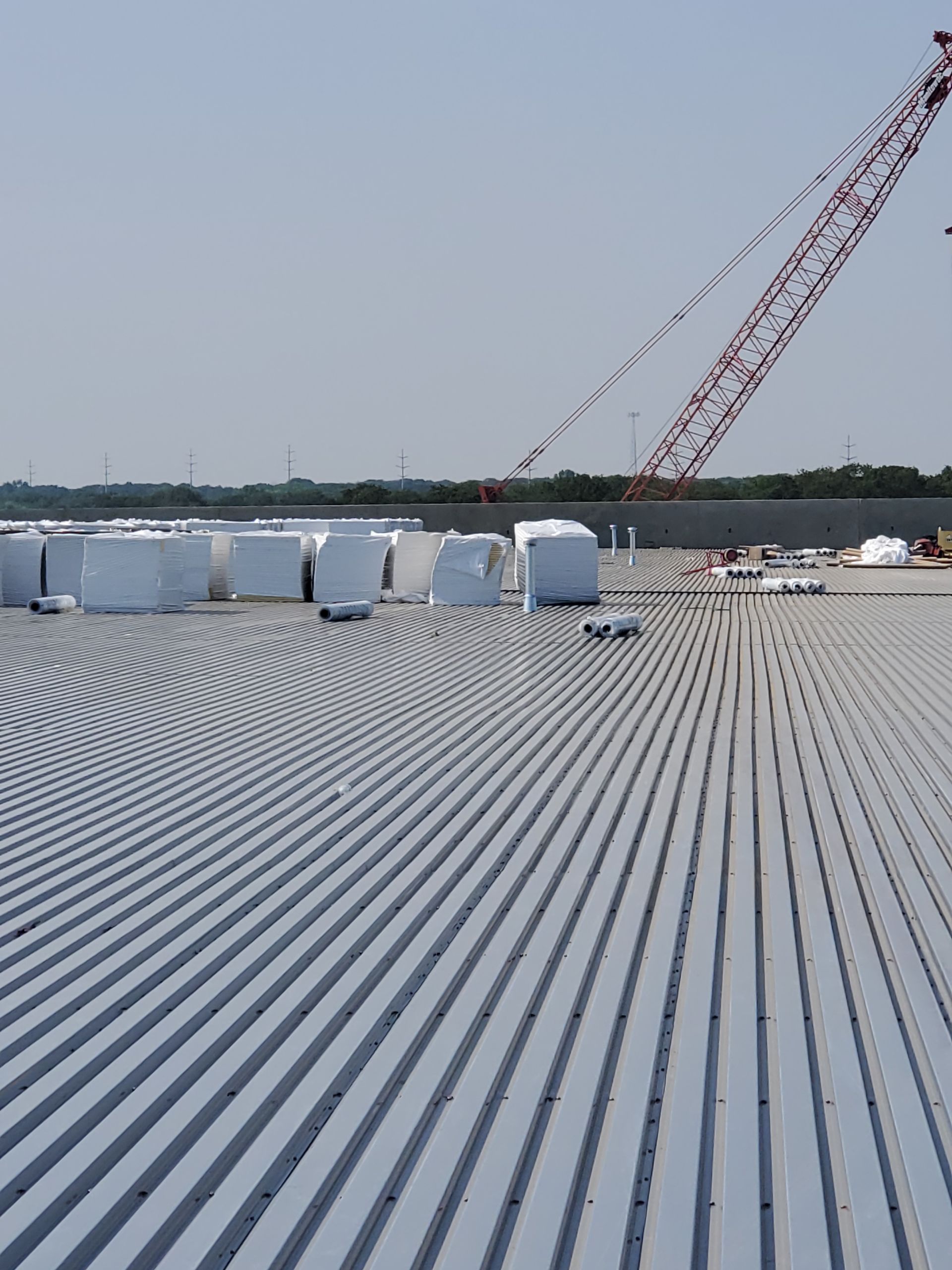 Metal roof with crane; construction site with wrapped materials.